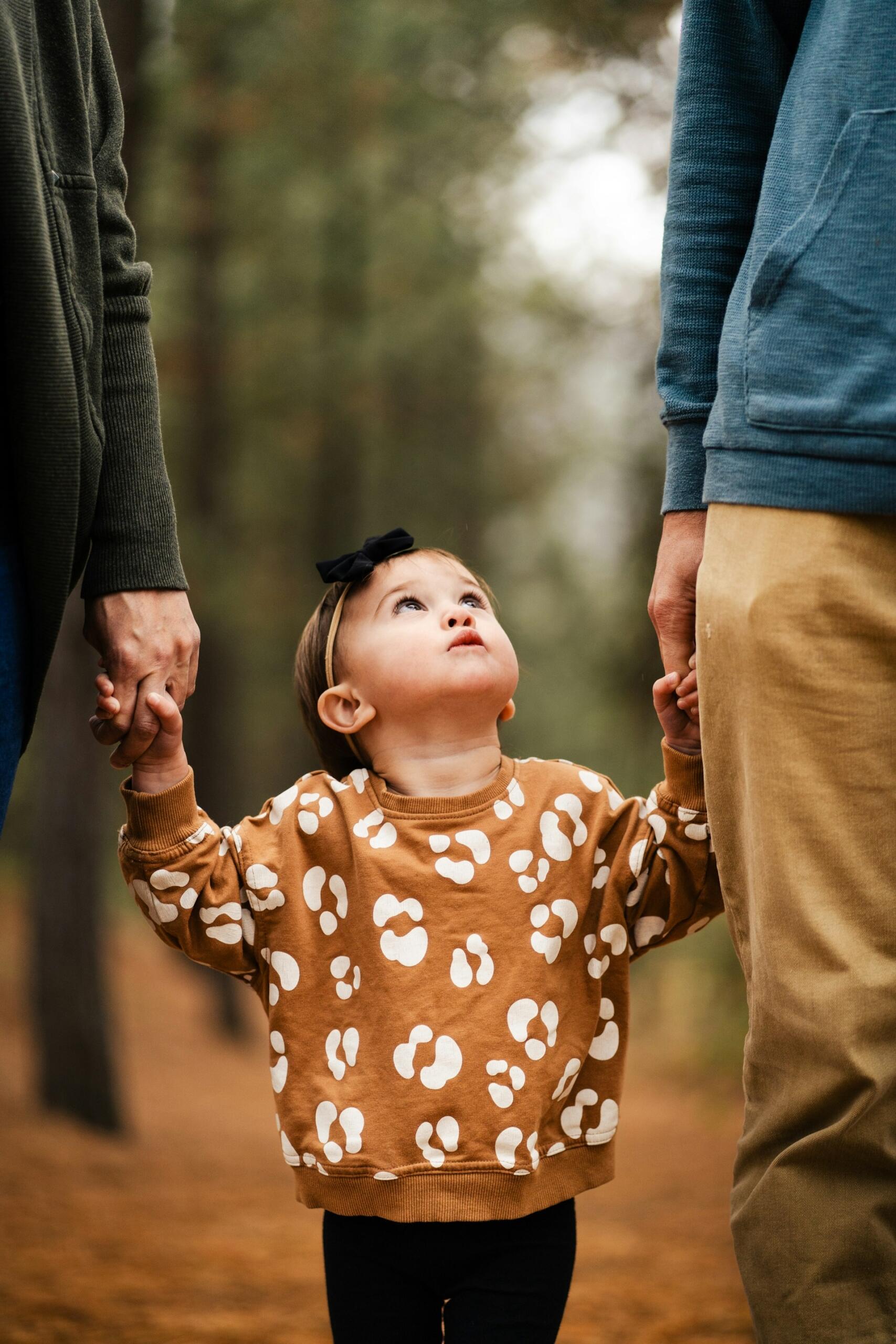 Niña agarrada de la mano de sus progenitores.