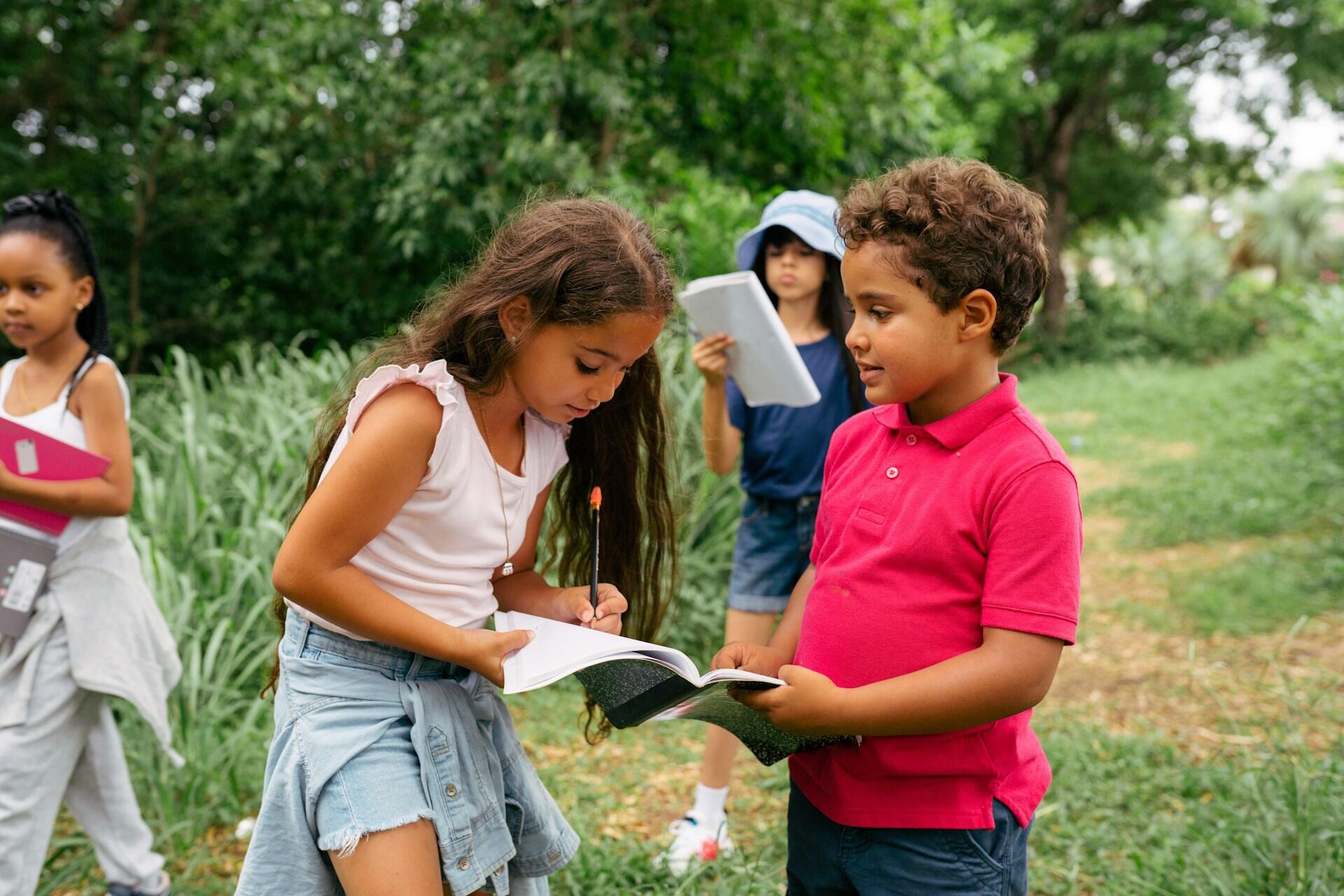 Niños escribiendo y jugando al aire libre.