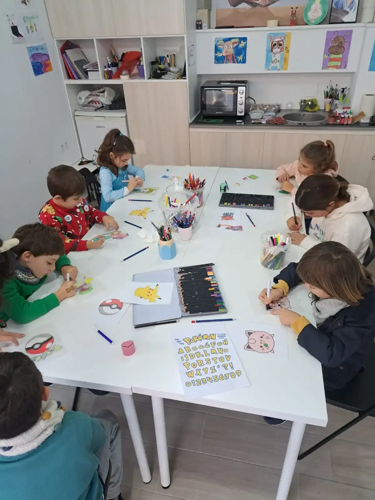 Un grupo de niños se dedicaba a hacer manualidades en una mesa, coloreando con rotuladores y lápices de colores varios diseños.