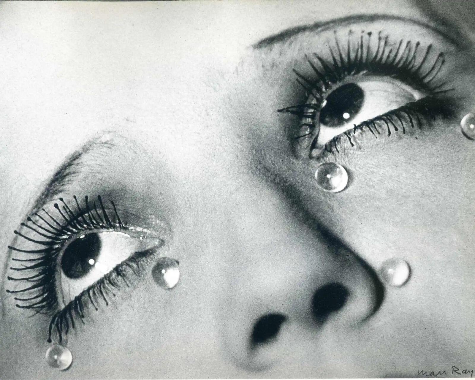 Foto en blanco y negro en primer plano de los ojos de una mujer mirando hacia arriba, adornados con grandes gotas de cristal reflectantes que parecen lágrimas. Emoción: surrealista y contemplativa.
