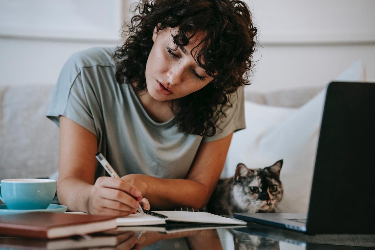 Chica trabajando con el gato al lado.
