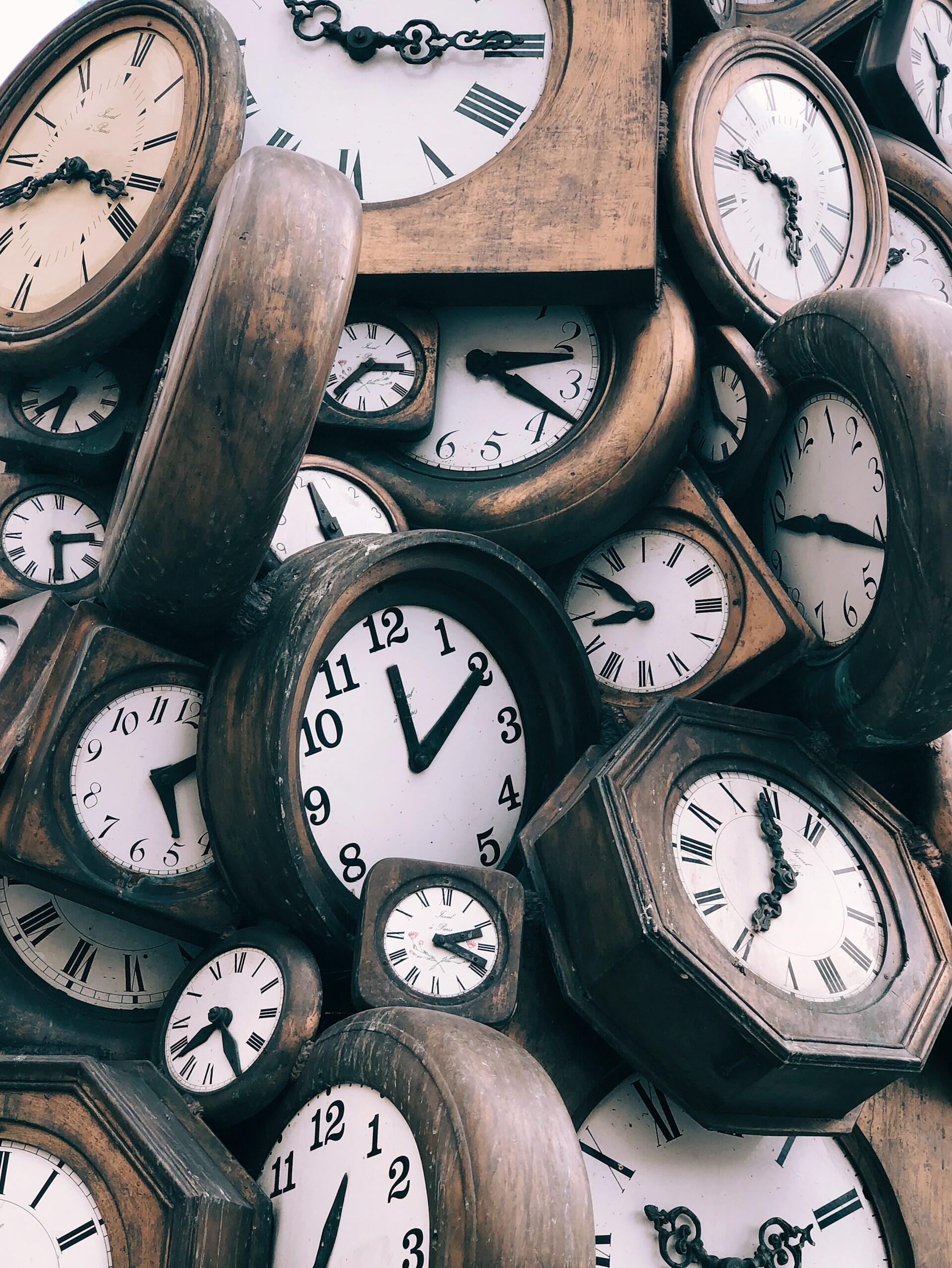 Un denso collage de relojes antiguos de madera con números romanos y agujas ornamentadas, que se superponen en distintos ángulos para crear un ambiente nostálgico.