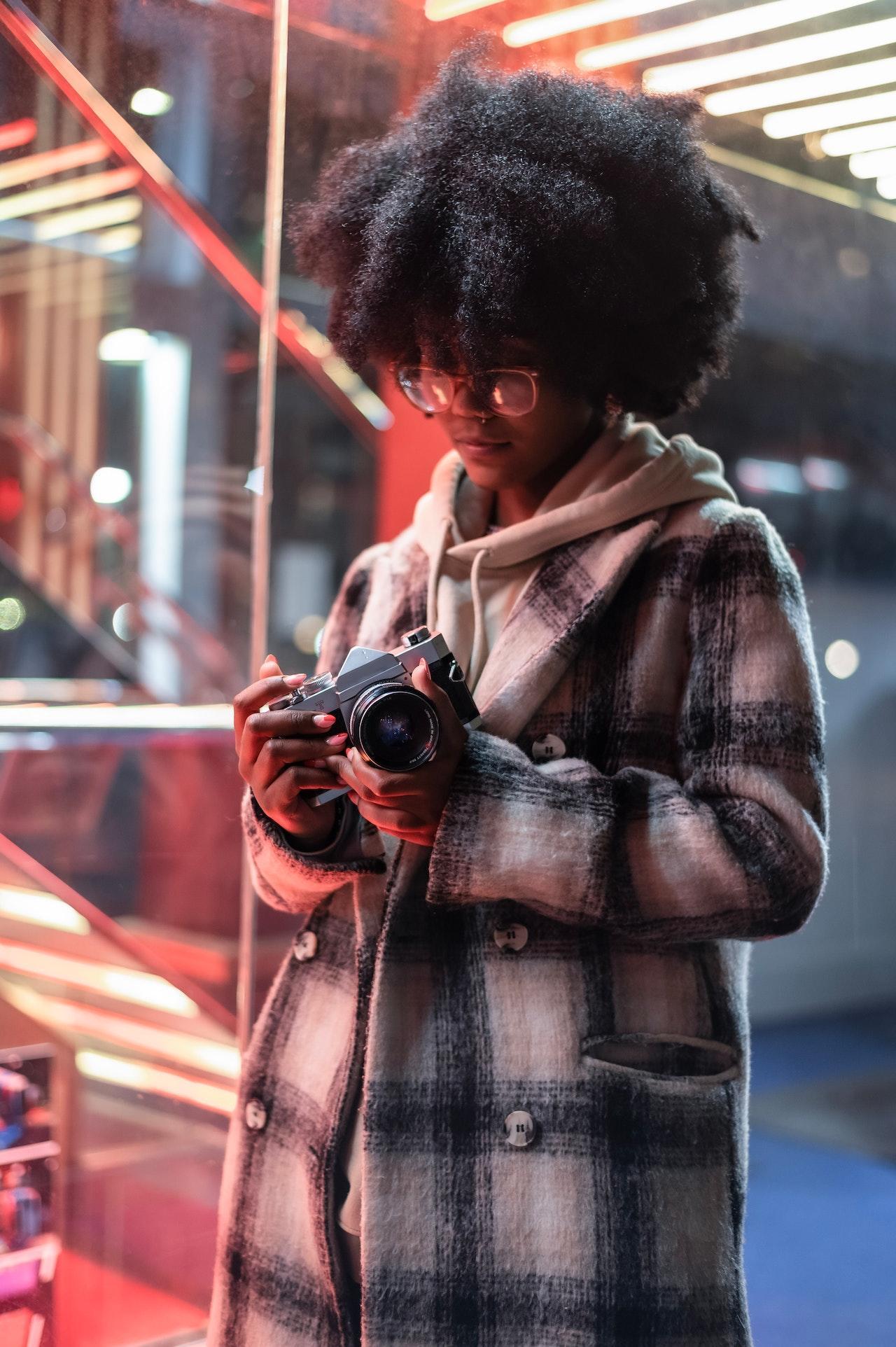 mujer con una camara reflex entre sus manos caminando por la ciudad
