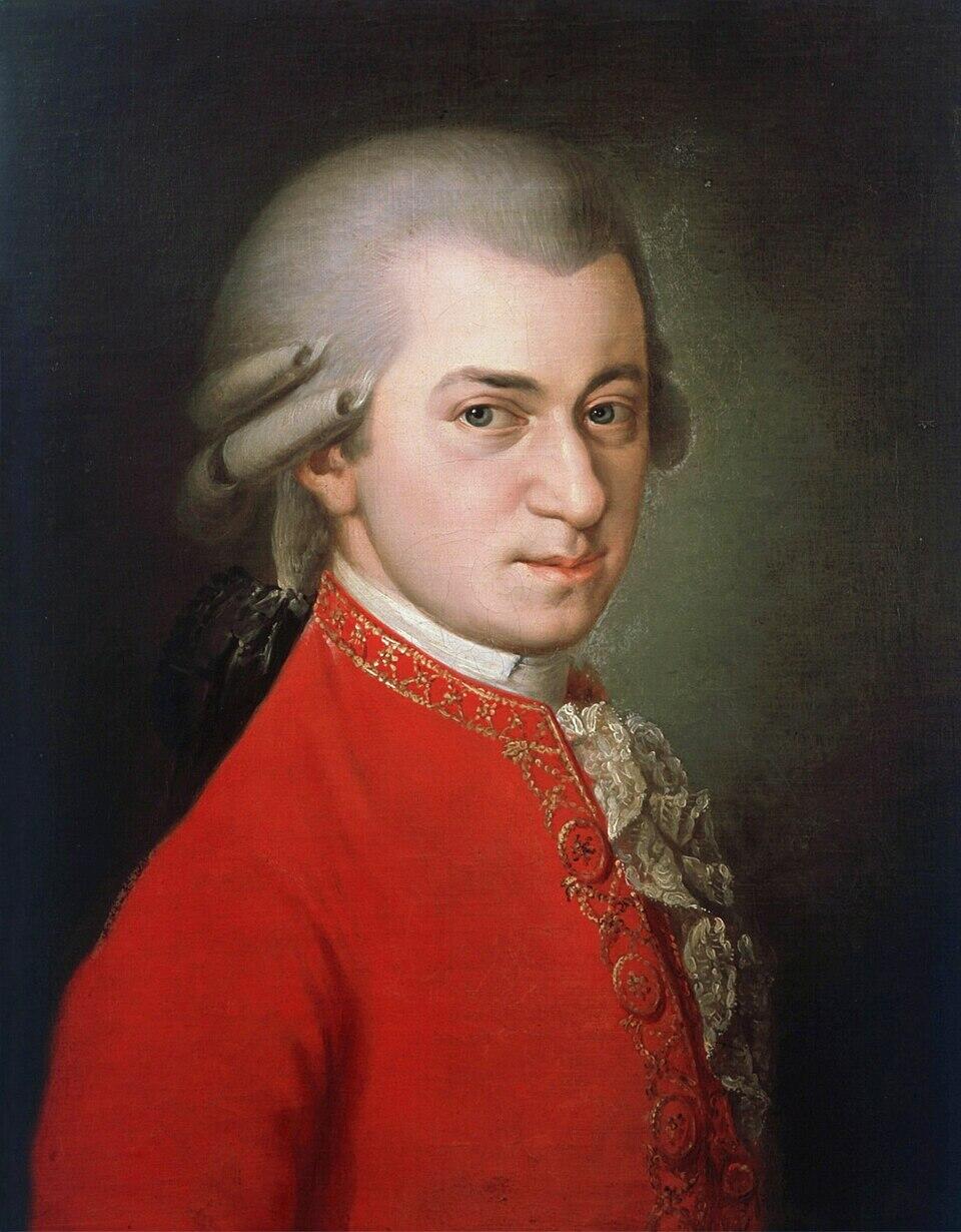 Retrato de Mozart con cabello blanco, vestido con una chaqueta roja ornamentada y corbata blanca, mirando ligeramente hacia la izquierda contra un fondo oscuro.