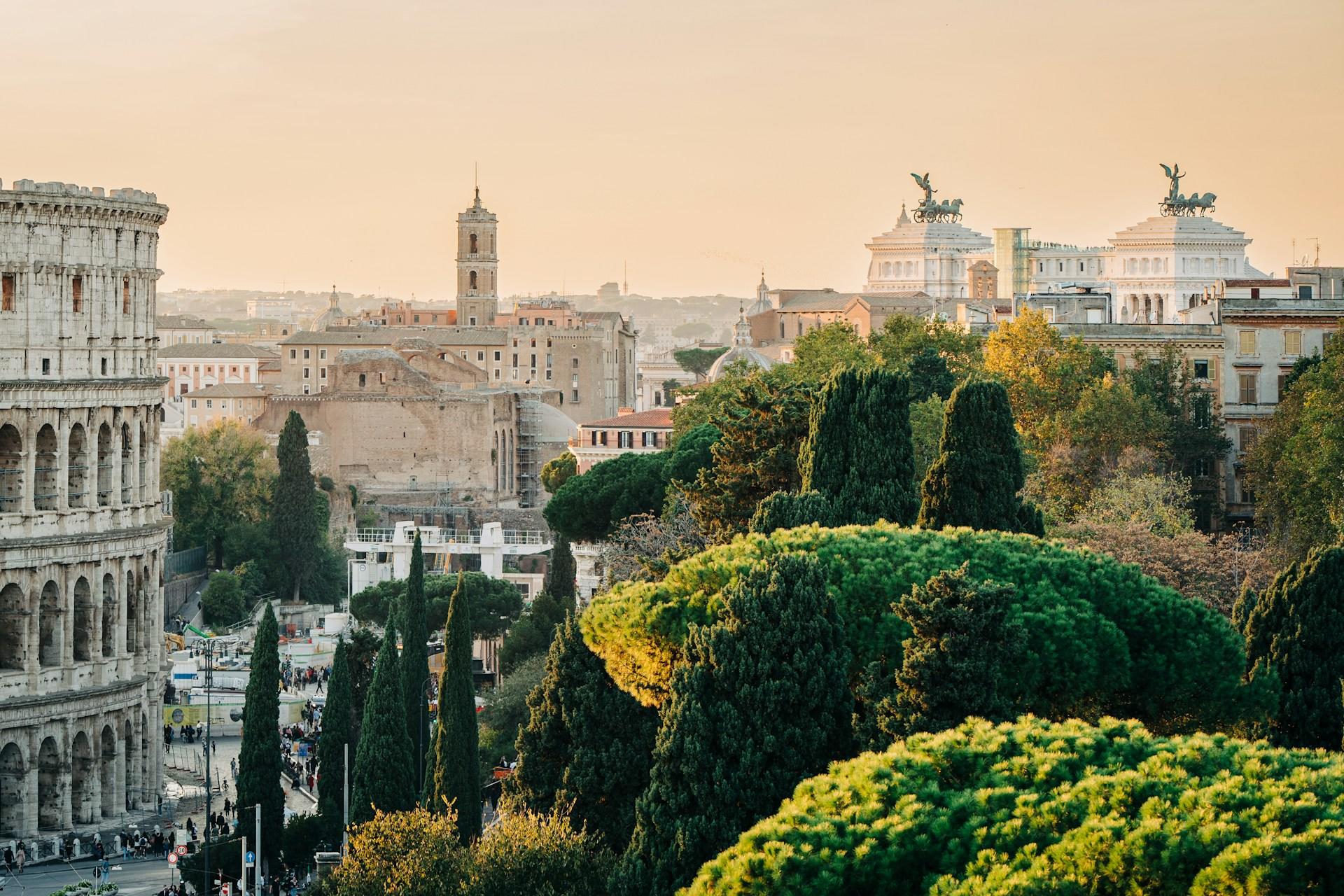 Vista en hora dorada del Coliseo y paisaje urbano con vegetación en Roma, Italia.