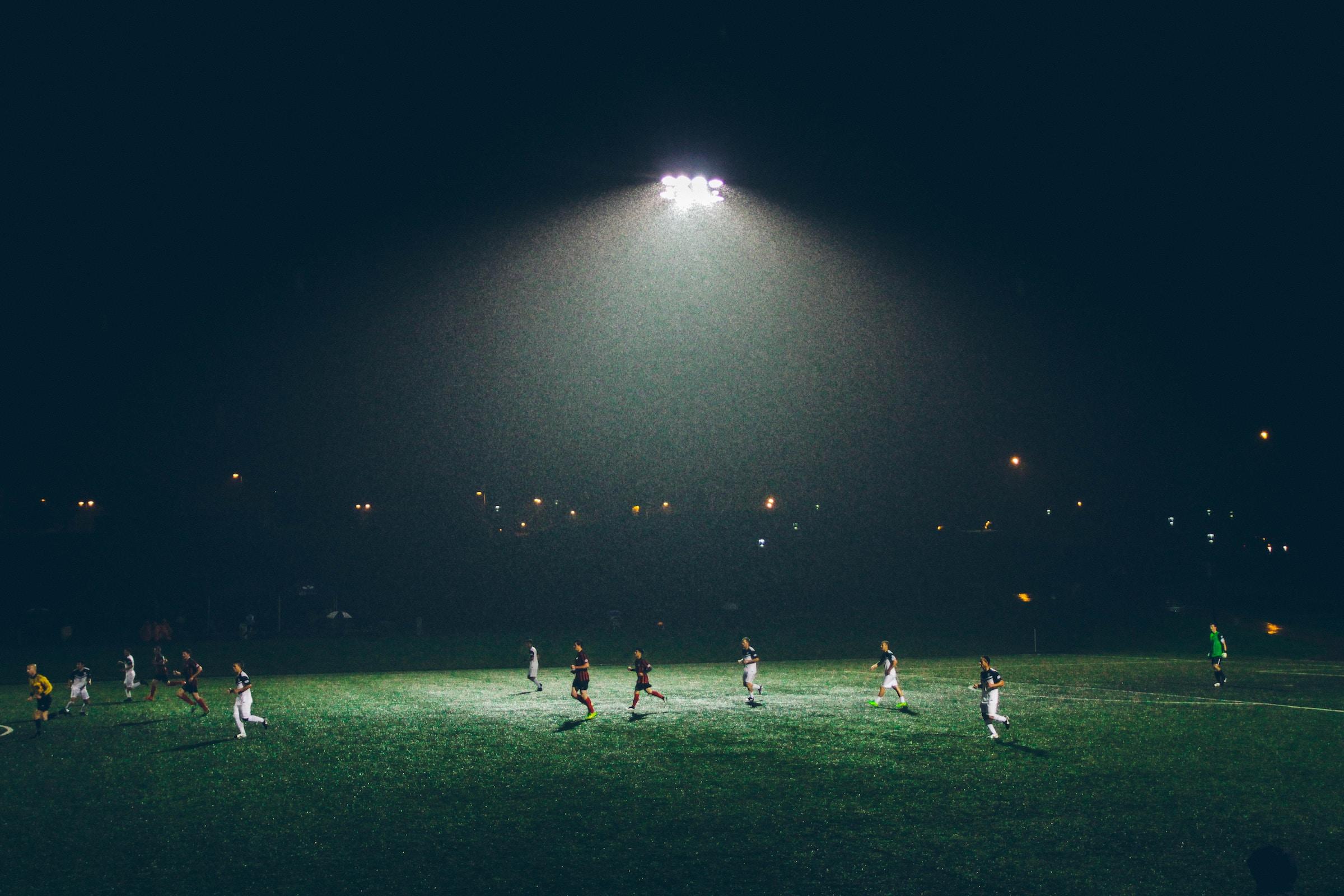 vista cancha de futbol de noche con jugadores en ella