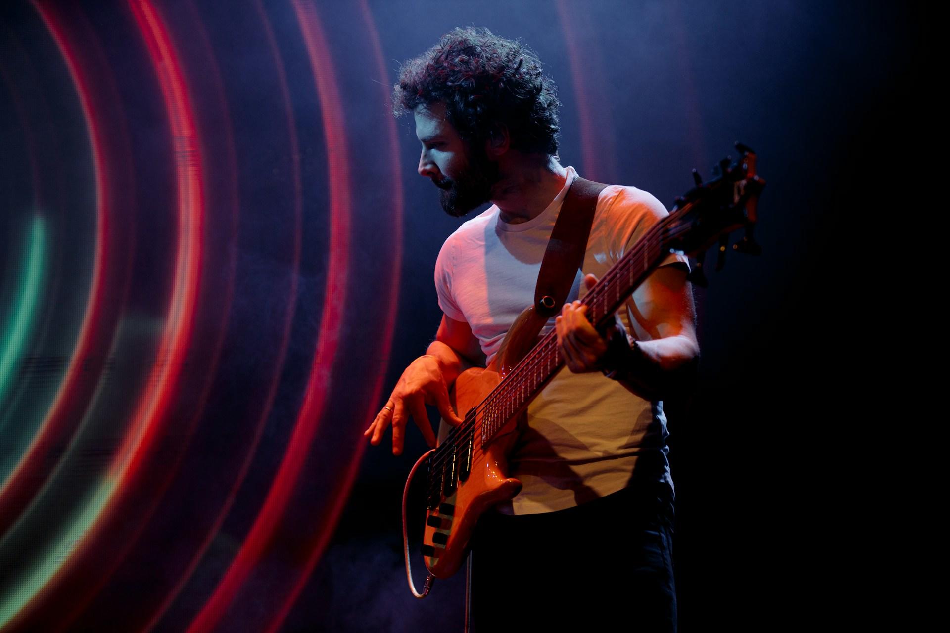 hombre en escenario de colores tocando guitarra