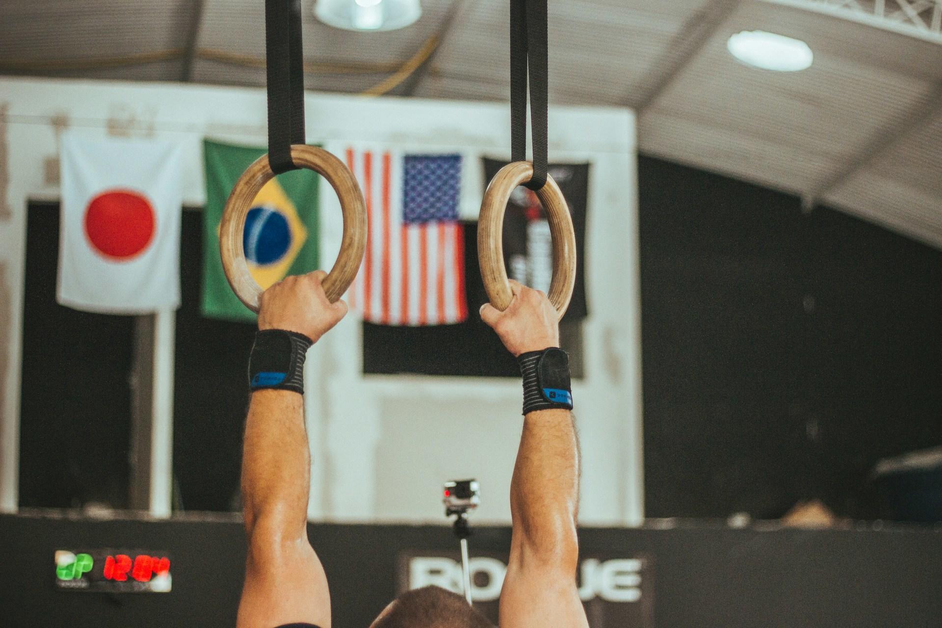 Persona colgada de unas anillas en un gimnasio.