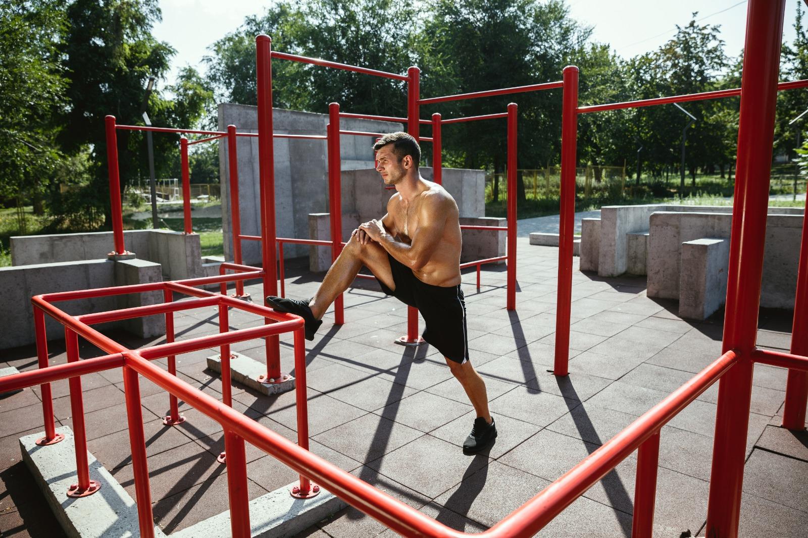 Hombre sin camiseta practicando calistenia en un parque de barras.