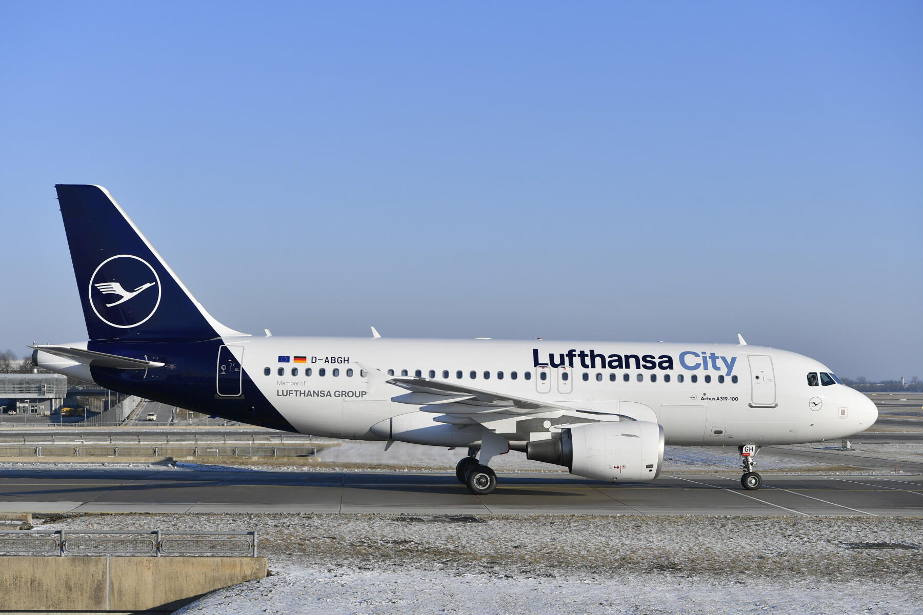 Un Airbus A319-100 de Lufthansa City rodando por una pista, mostrando su distintiva decoración blanca y azul contra un cielo despejado.