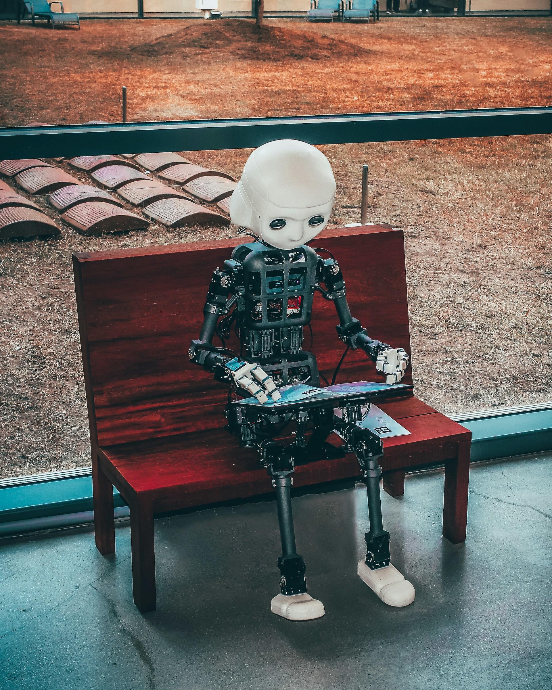 robot trabajando en computadora sentado en un banco rojo