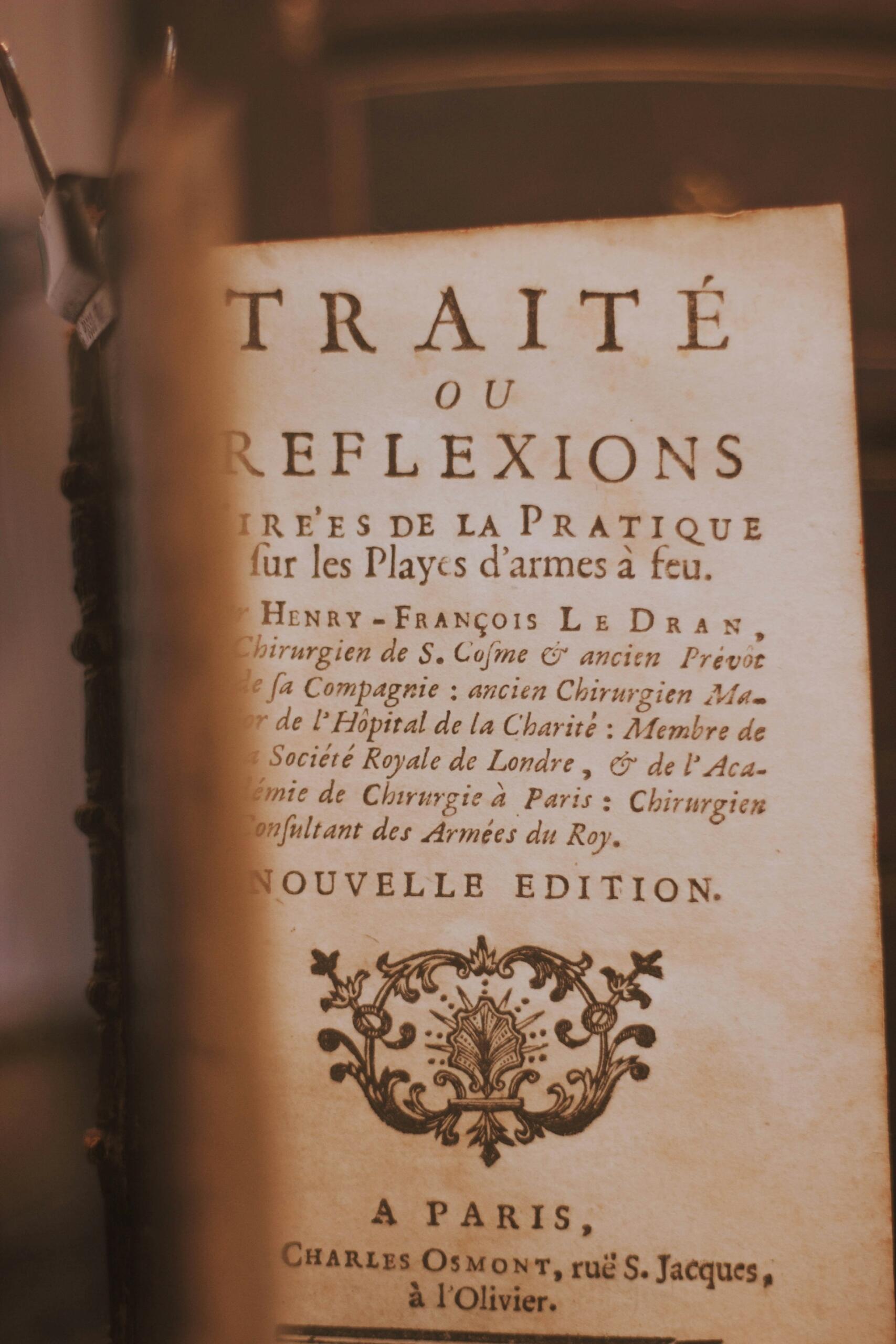 Un antiguo libro de medicina francés titulado «Traité ou Réflexions», con un emblema ornamentado, páginas desgastadas y una cálida iluminación de época que crea un ambiente erudito.