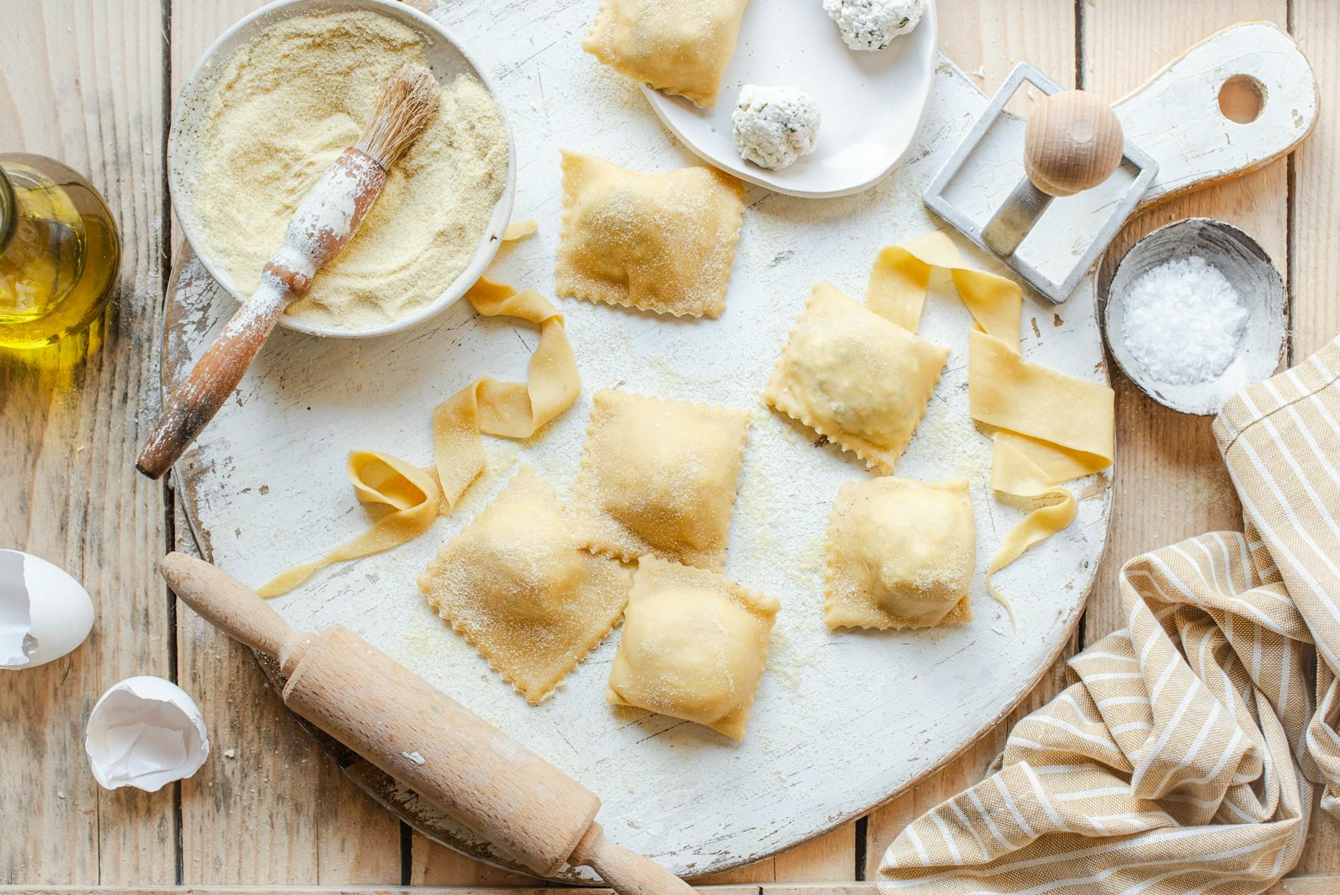 un plato blanco de raviolis junto a un bowl de queso
