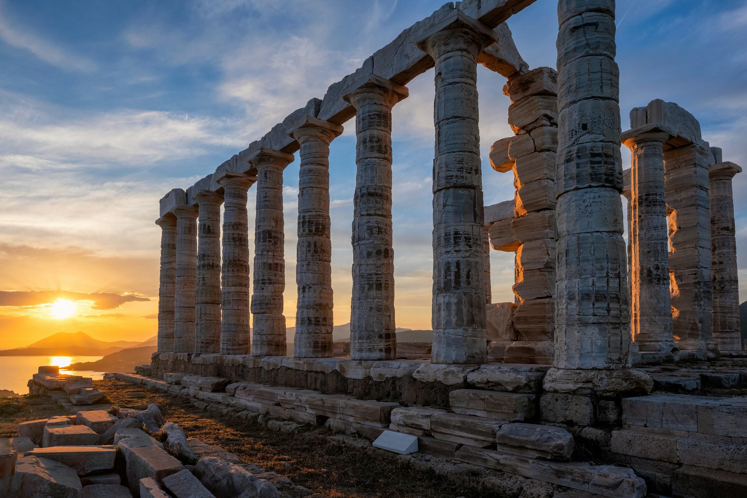 Puesta de sol tras las ruinas de un antiguo templo griego con columnas dóricas.