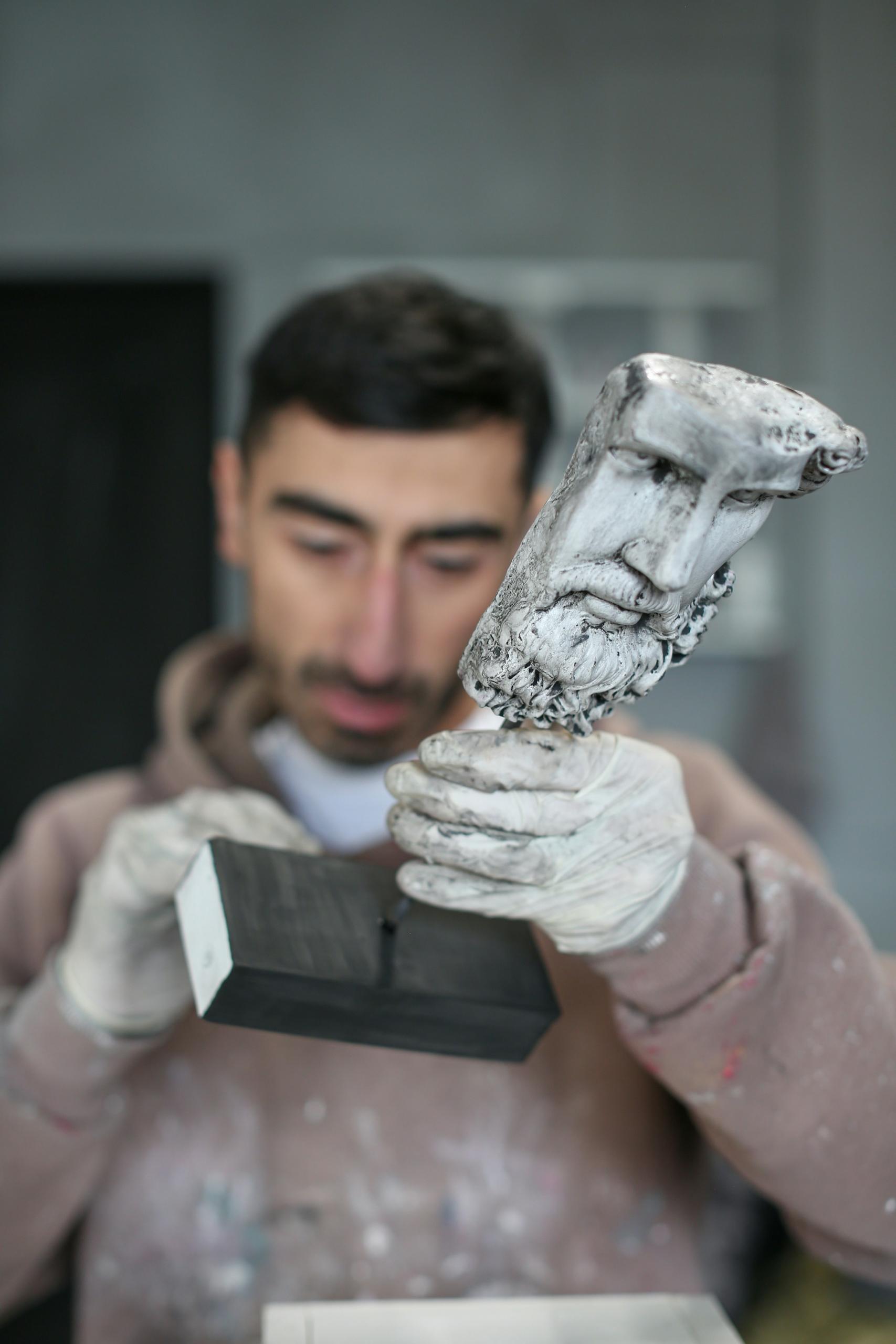 Persona analizando una escultura antigua de la cara de un hombre 
