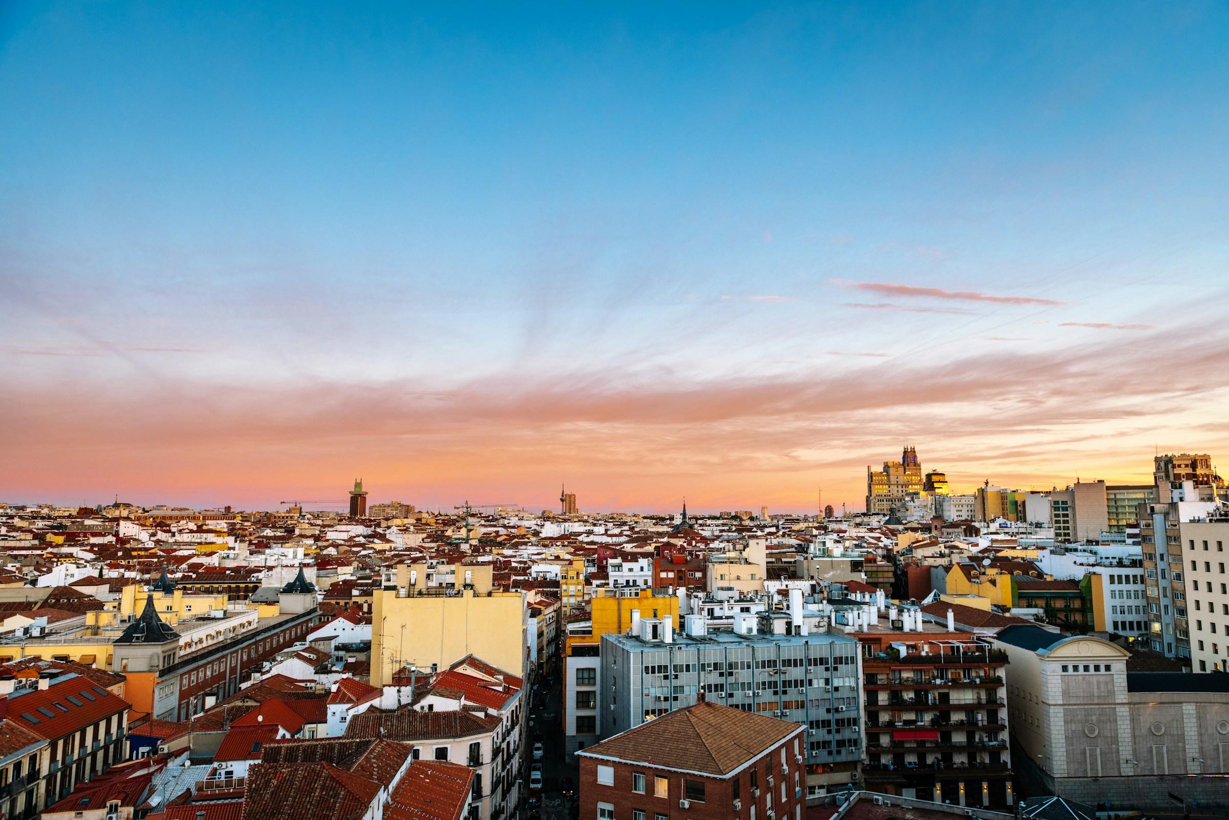 Puesta de sol sobre un denso paisaje urbano con edificios de colores y cielos despejados de madrid