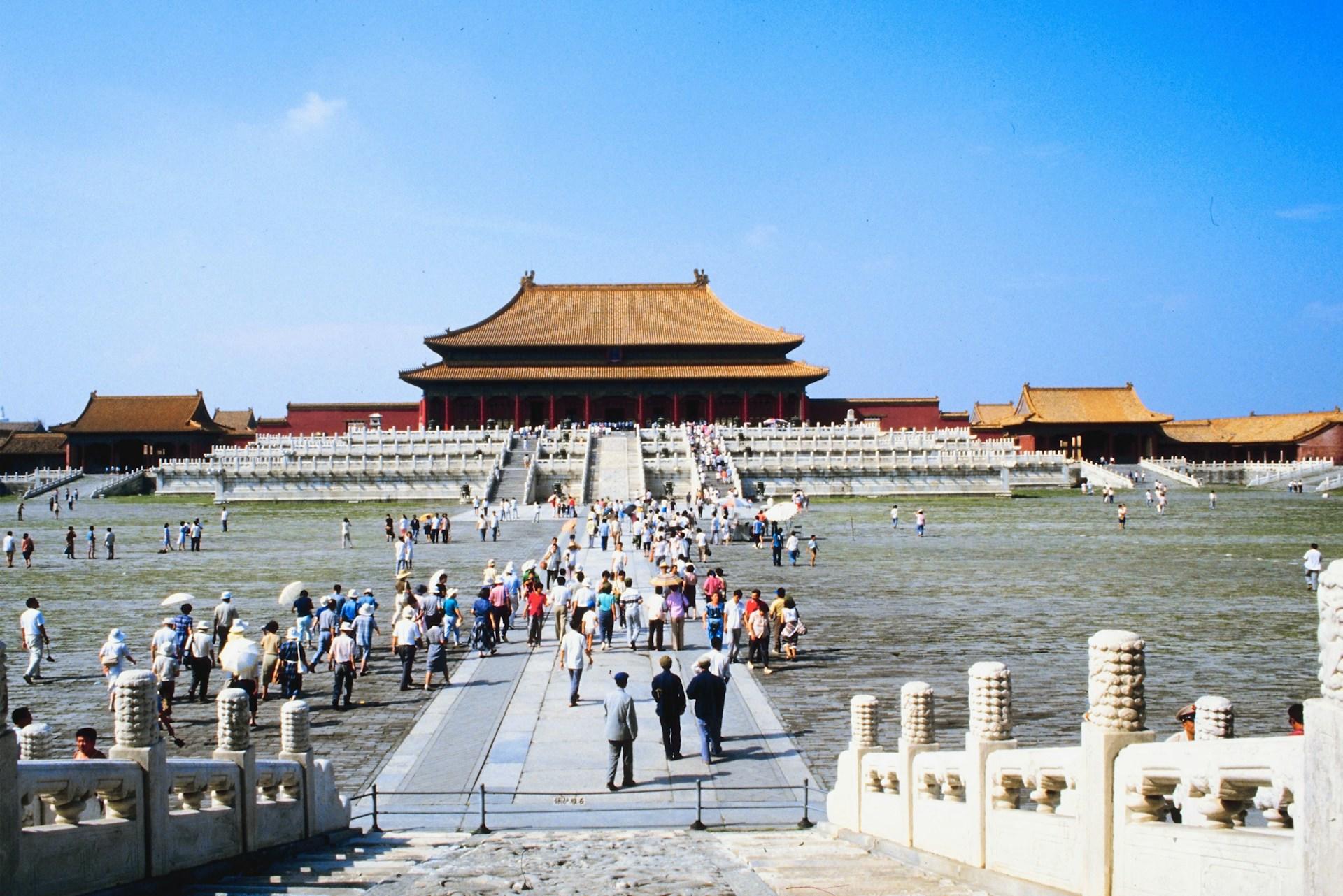 Visitantes en la Ciudad Prohibida de Pekín, con arquitectura histórica bajo un cielo azul.