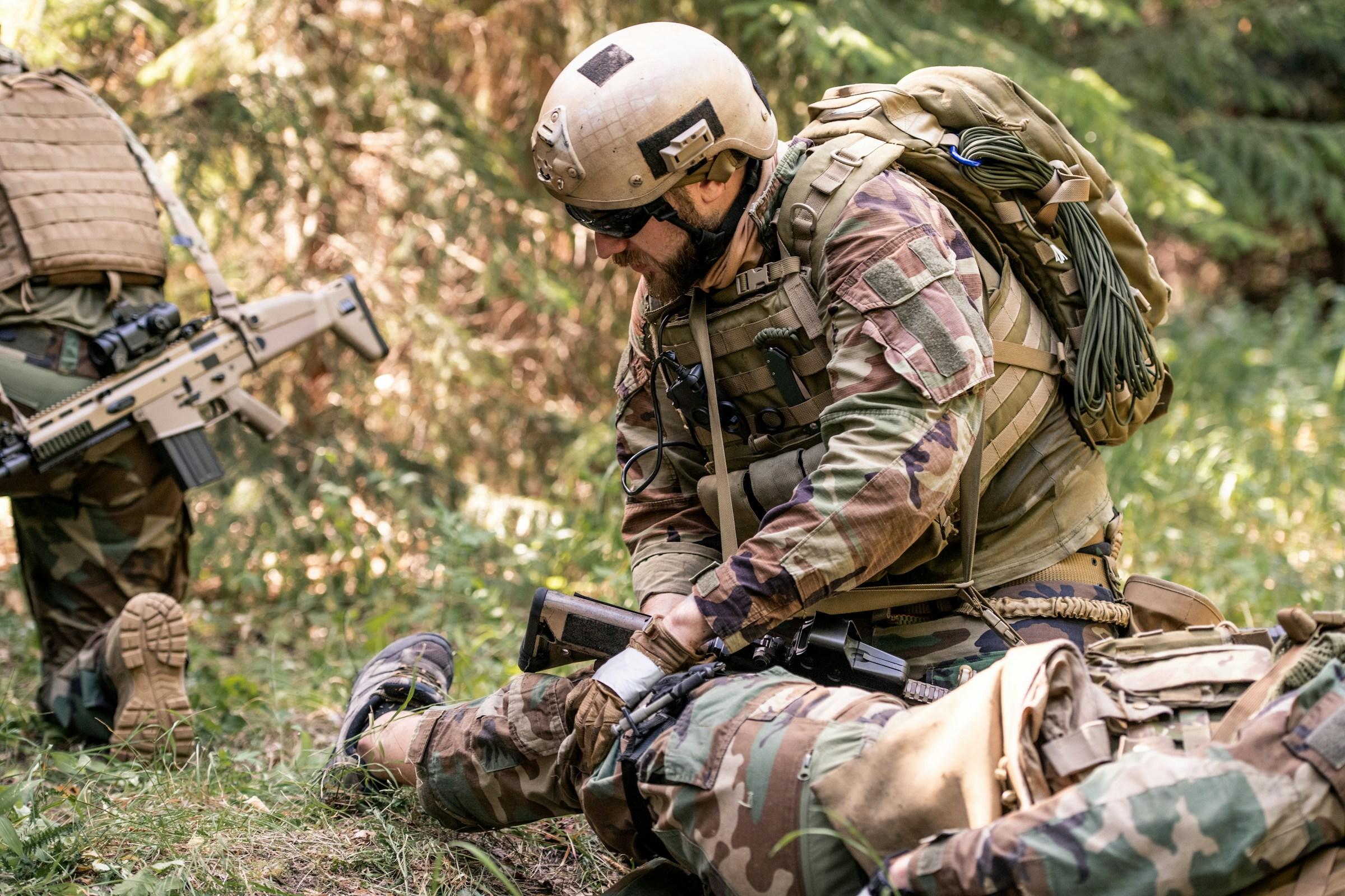 Soldados con equipo de camuflaje agazapados en un bosque con equipo táctico.