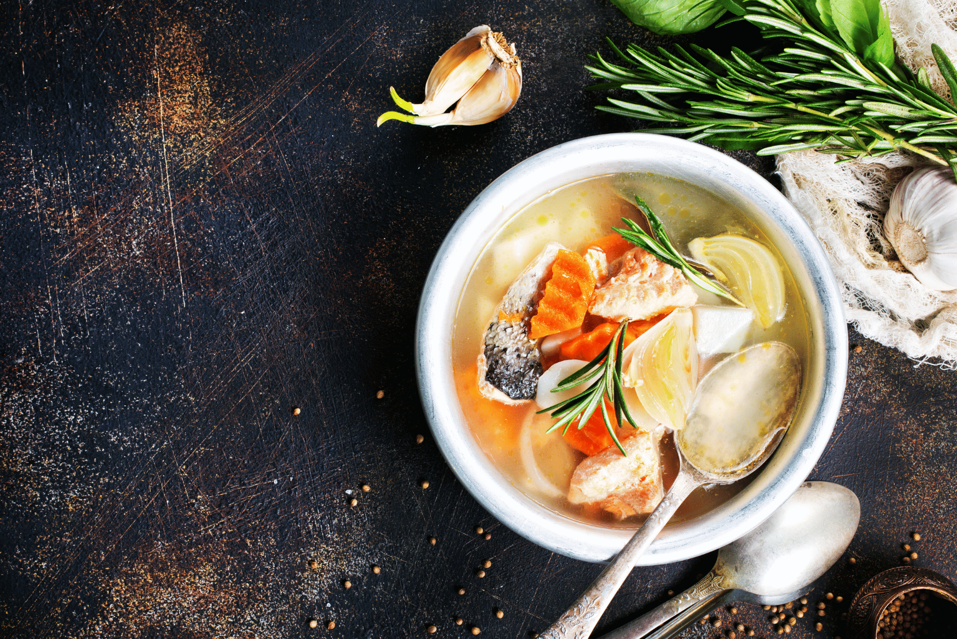 Un tazón de sopa de merluza humeante con verduras frescas y hierbas aromáticas.