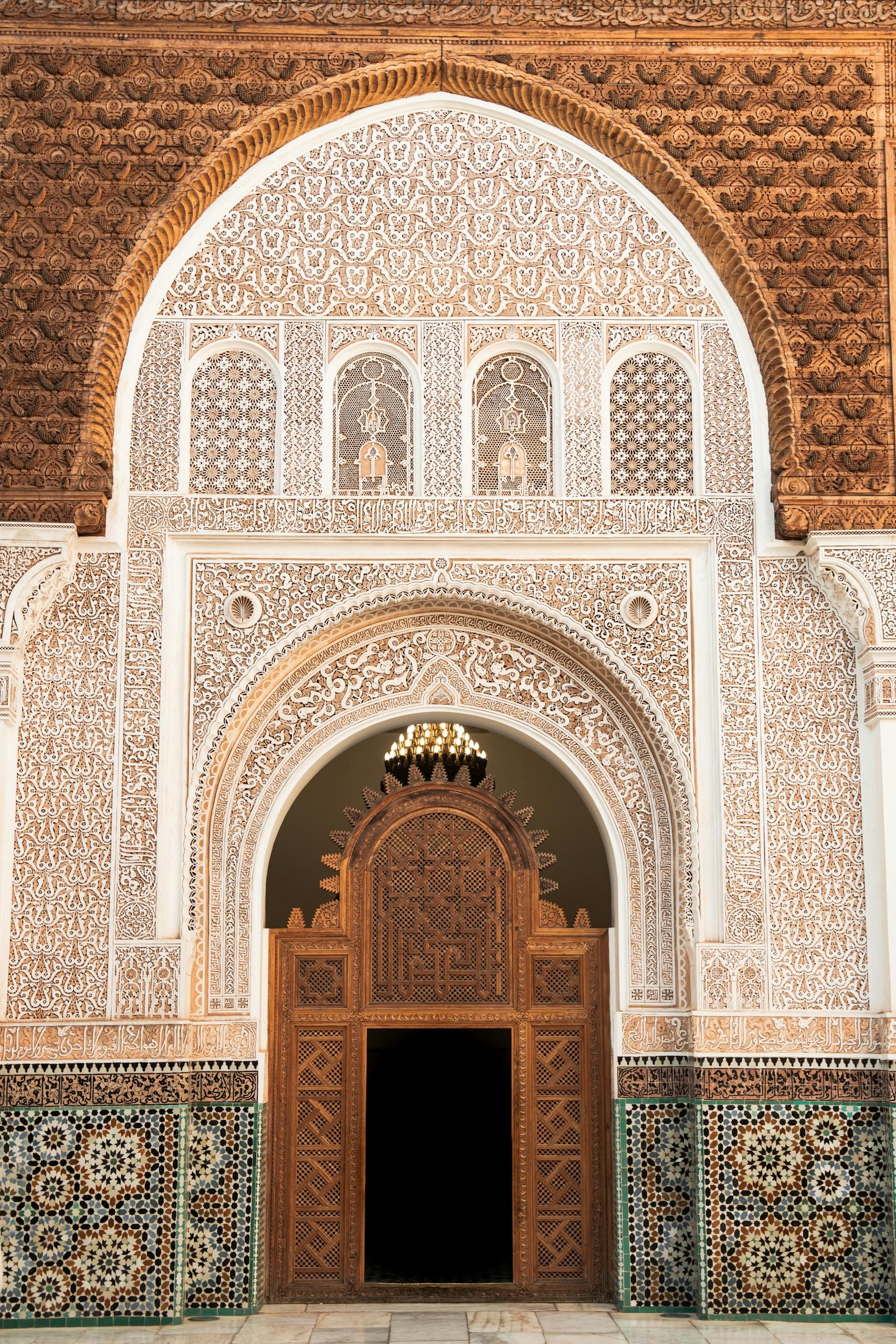 Arco ornamentado con intrincados azulejos y puerta de madera tallada de estilo arquitectónico morisco de la alhambra