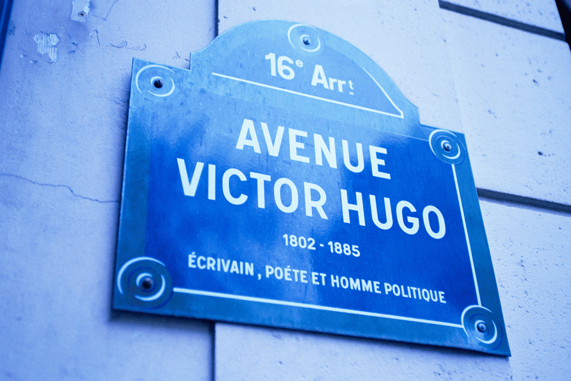 Letrero de la calle «Avenue Victor Hugo» con las vidas y profesiones en una placa azul.