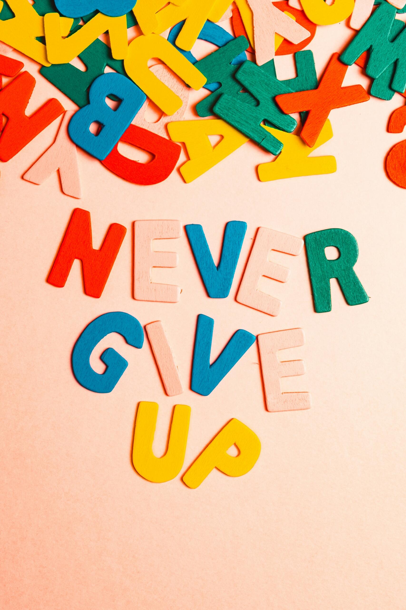 Letras de colores que dicen «NUNCA TE RINDAS» sobre fondo melocotón.