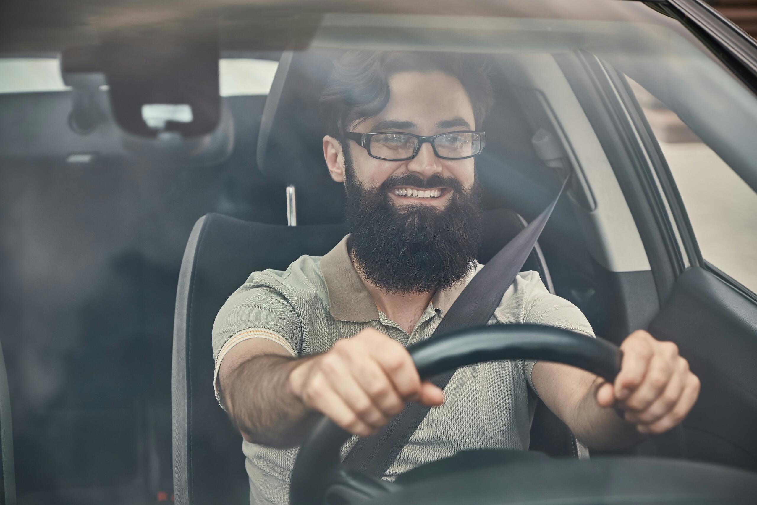 Hombre conduciendo un coche con las manos en el volante y llevando puesto el cinturón de seguridad.