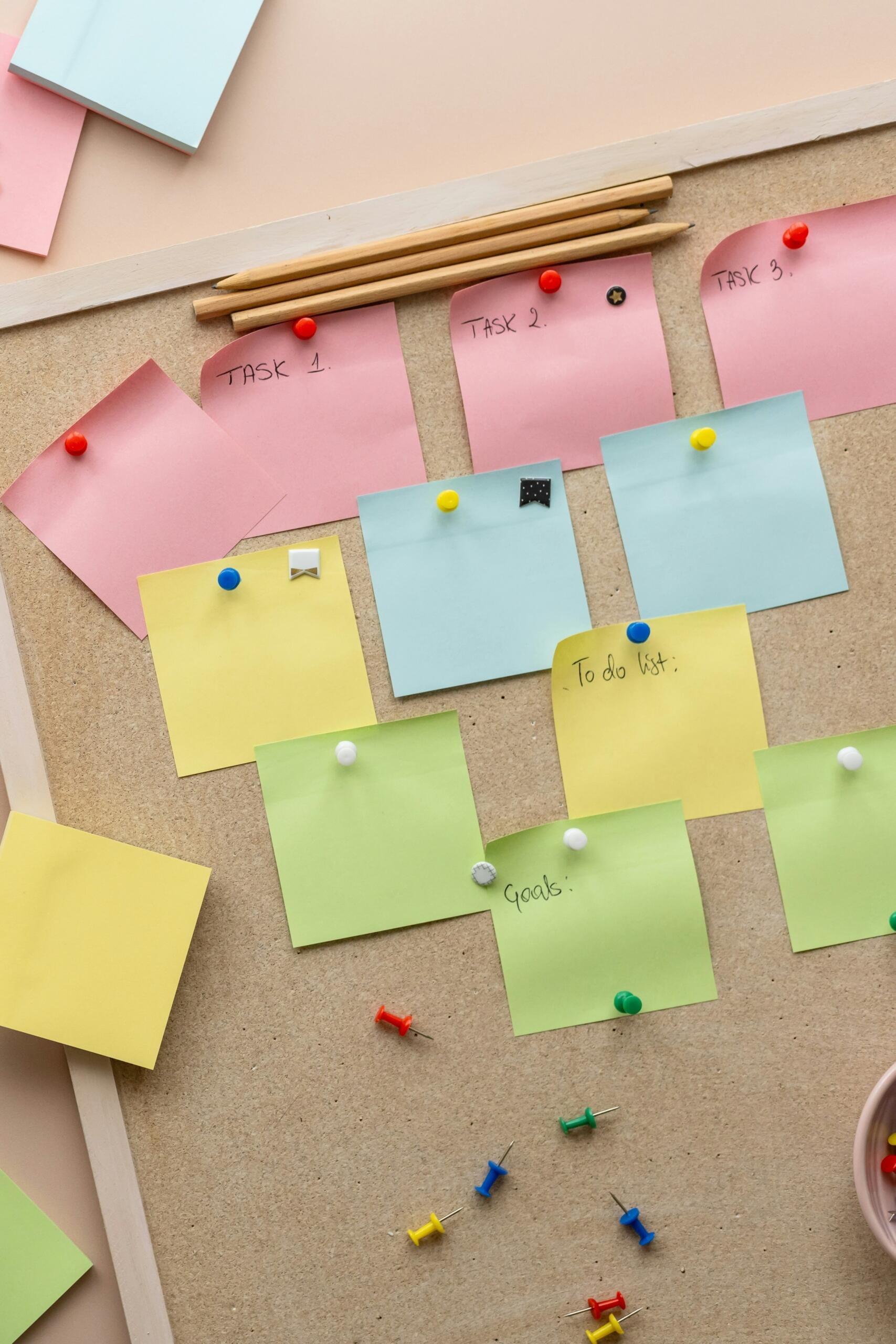 Una pizarra de corcho con notas adhesivas de colores y chinchetas para indicar tareas y objetivos.