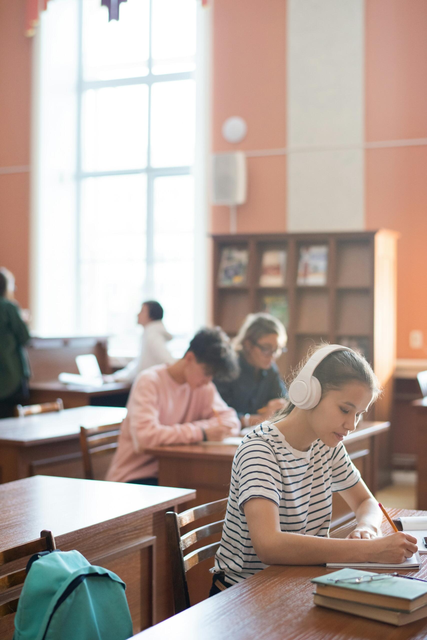 Alumnos sentados y estudiando en un aula muy iluminada con grandes ventanales.