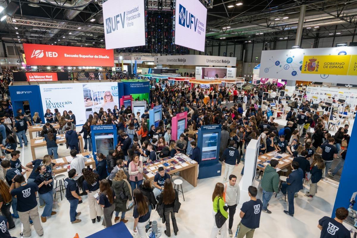 Una bulliciosa feria universitaria con numerosos puestos y carteles llamativos, repleta de asistentes que participan en debates. El ambiente es animado y enérgico.