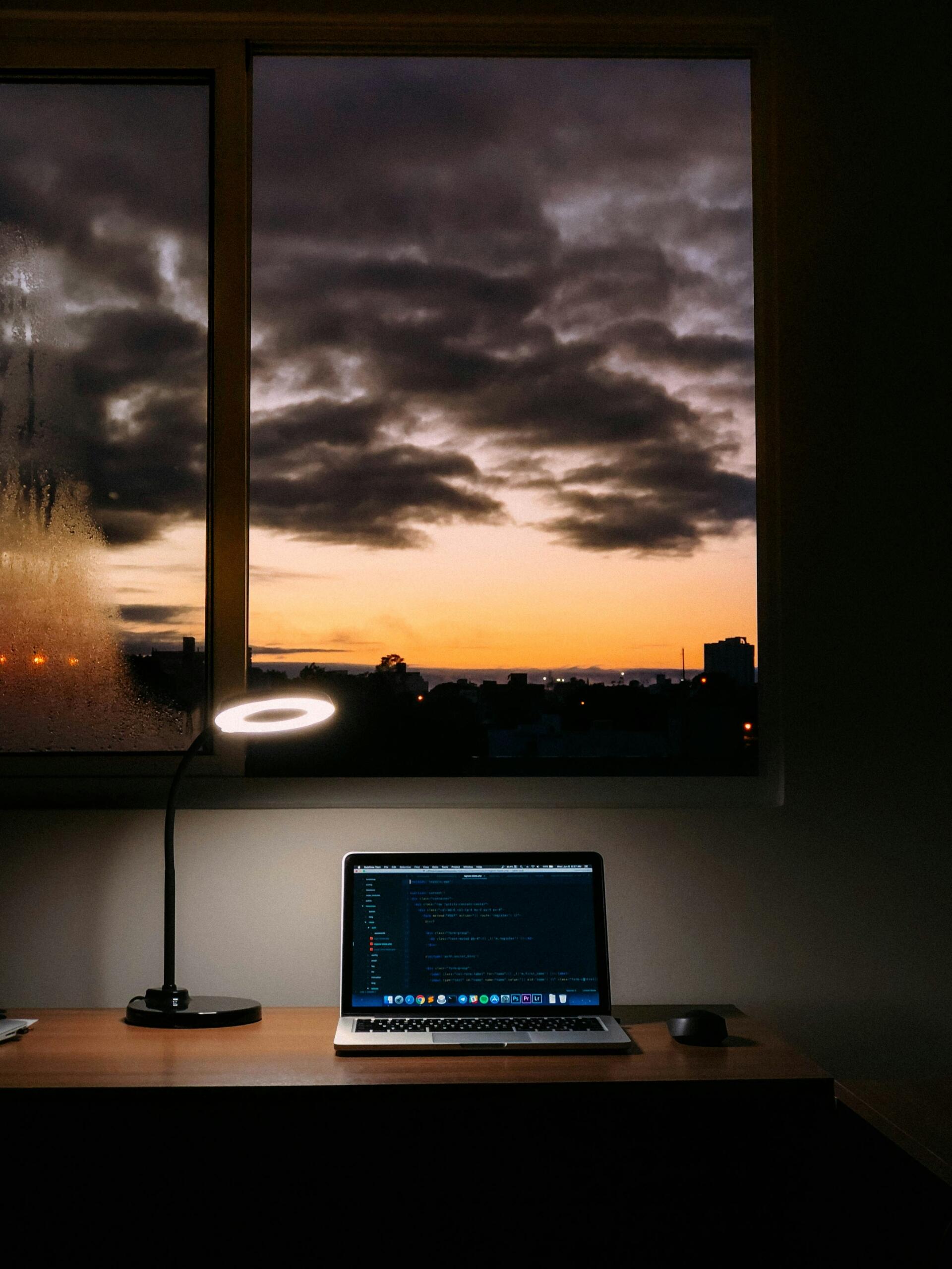Un portátil sobre un escritorio iluminado por una lámpara, creando un ambiente de trabajo acogedor y funcional.