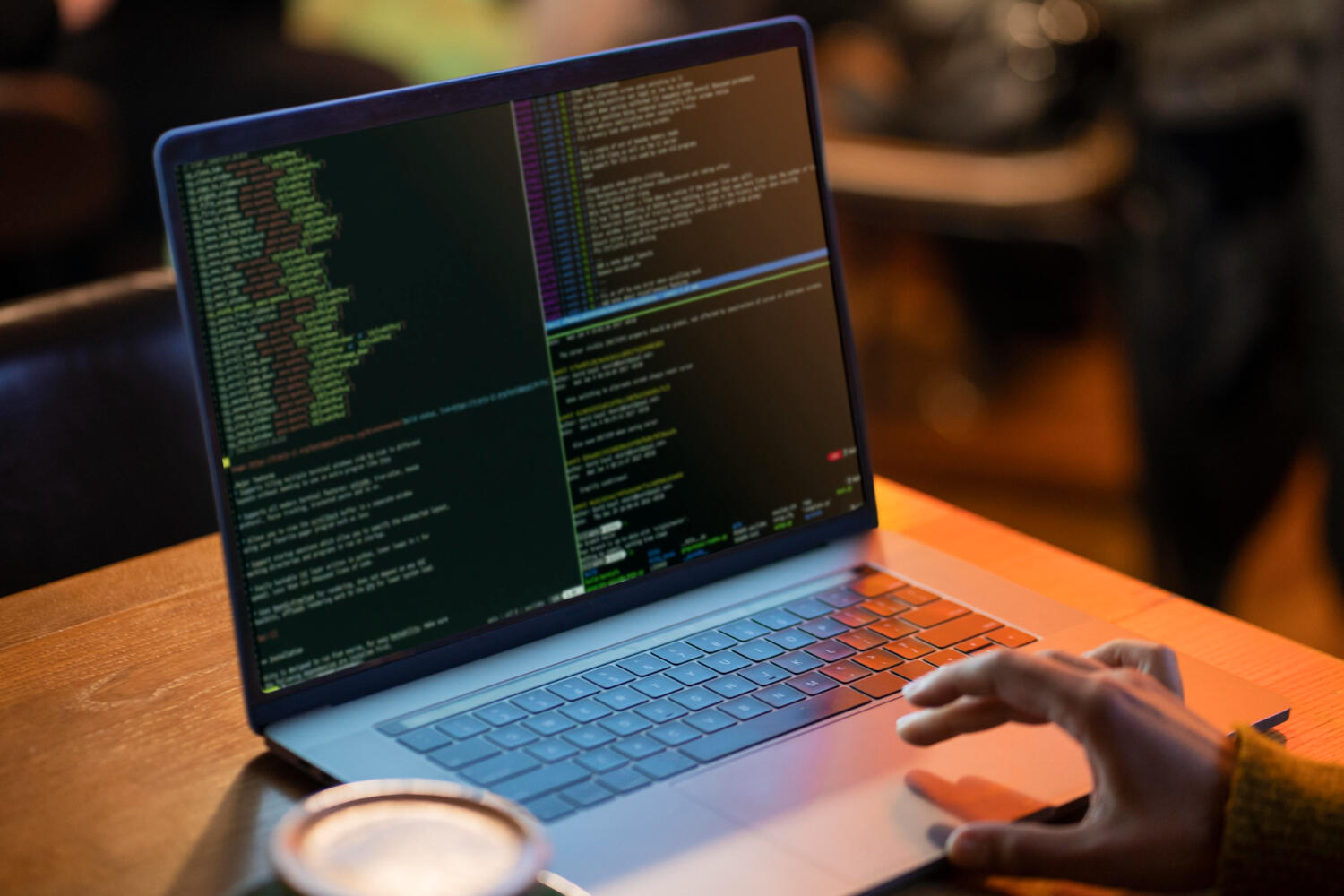 Persona tecleando en un portátil con código visible en la pantalla, concentrada en su trabajo de programación.