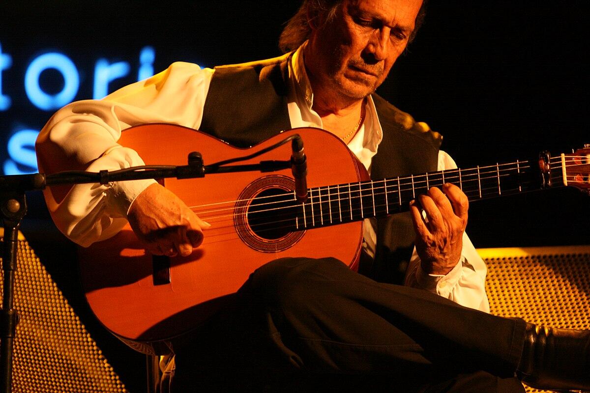 el guitarrista paco de lucia toca con pasión una guitarra clásica en el escenario, mostrando un intrincado juego de dedos y el cálido resplandor de una iluminación espectacular.