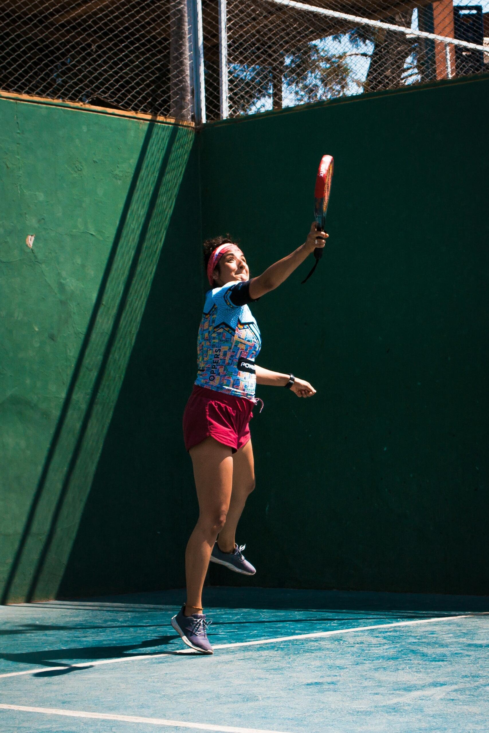 Mujer jugando pádel en una cancha, concentrada en el juego.