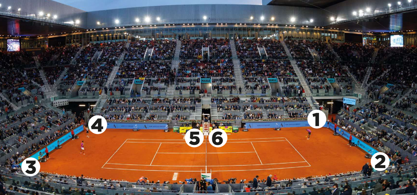 Un estadio de tenis abarrotado al anochecer, con jugadores en la red y aficionados entusiastas en las gradas, creando una atmósfera eléctrica.