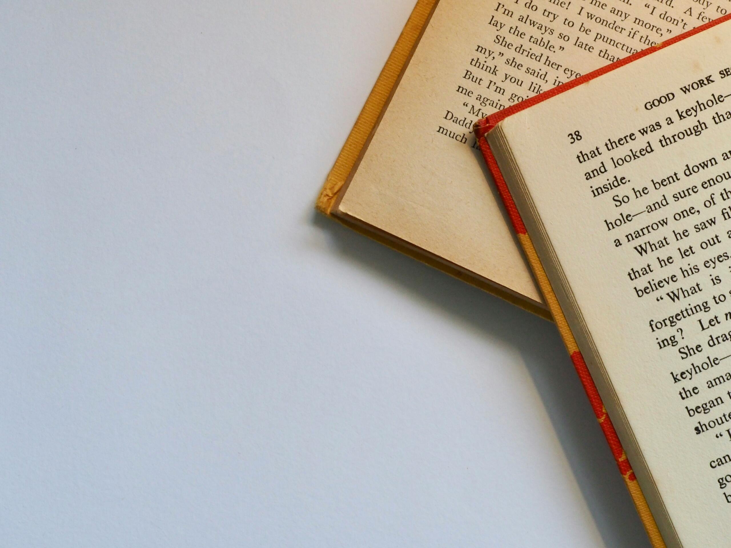 Dos libros abiertos descansan sobre una mesa blanca.