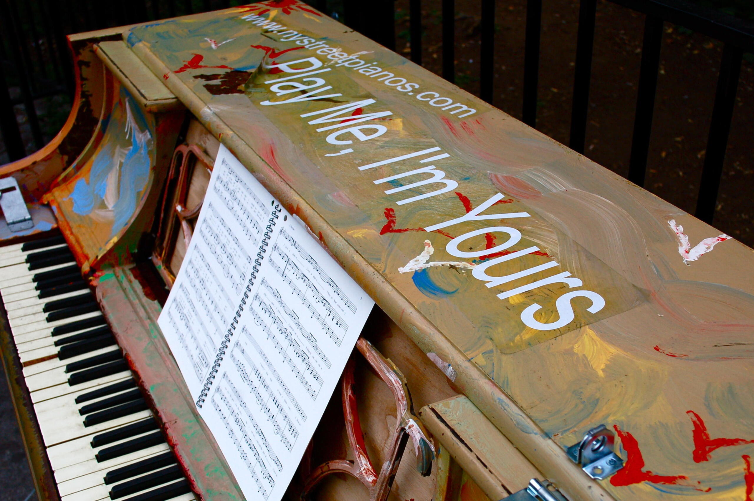 "Play me, I'm yours" encima de un piano.
