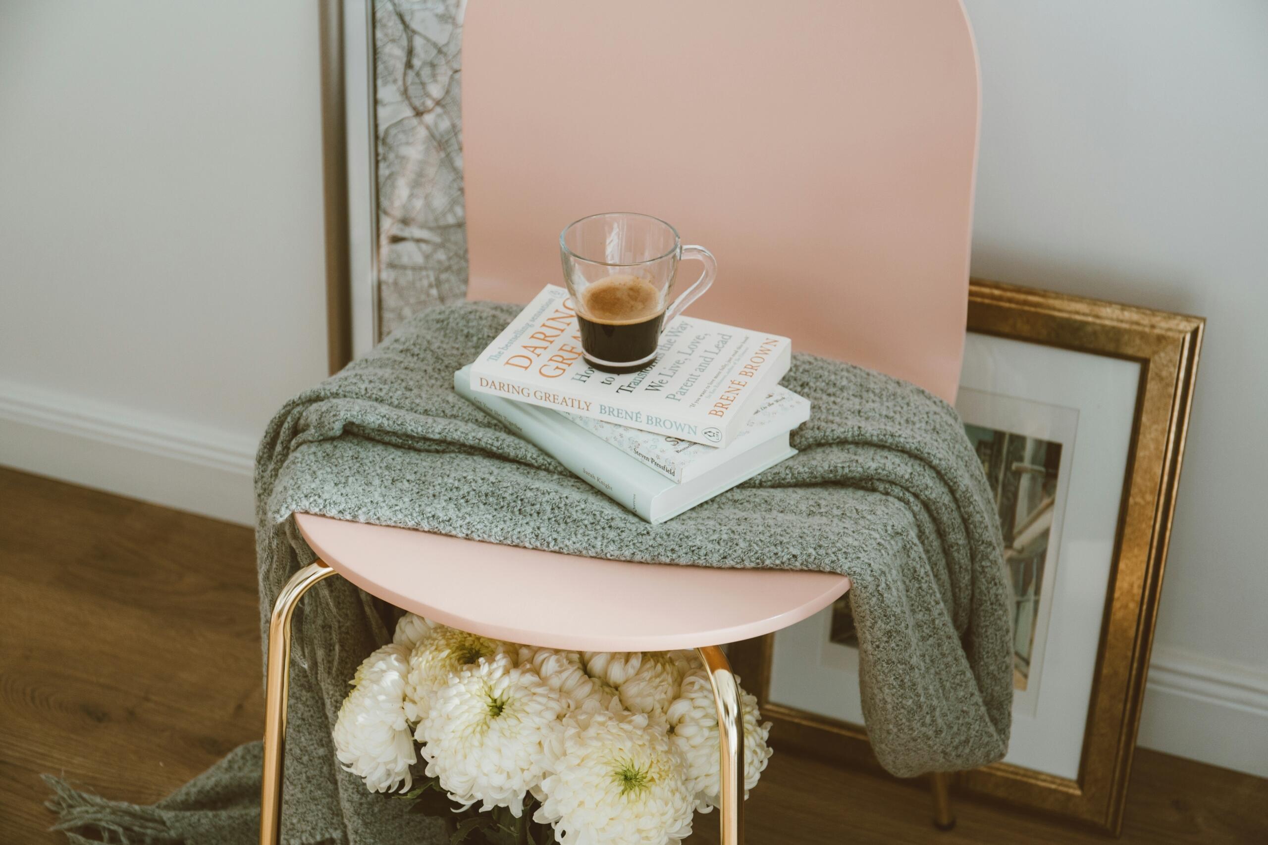 1. Silla rosa con un libro abierto y una manta enrollada sobre el asiento, creando un ambiente acogedor y relajante.