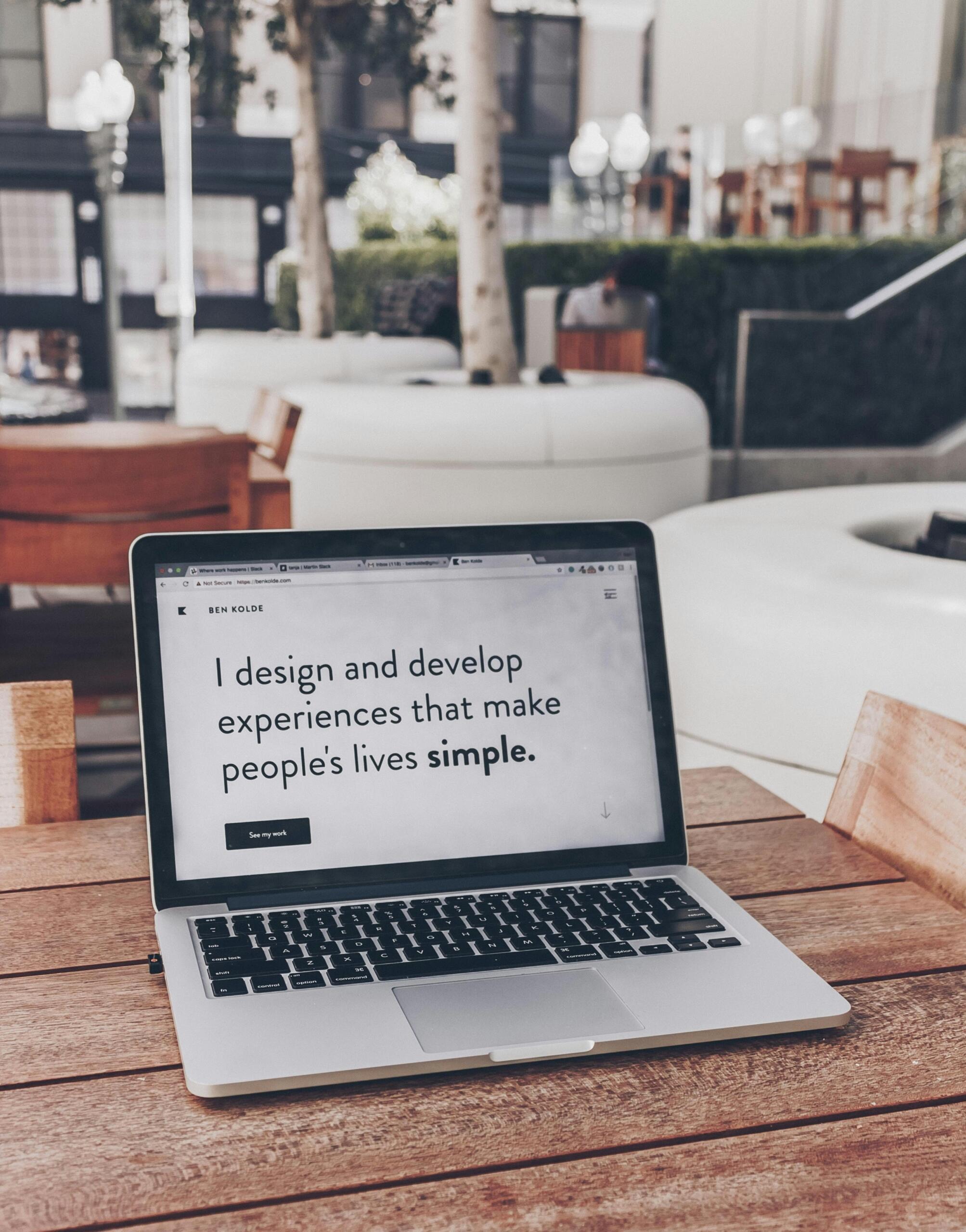 Un portátil sobre una mesa de madera muestra una página web en la que se lee: «Diseño y desarrollo experiencias que simplifican la vida de las personas».
