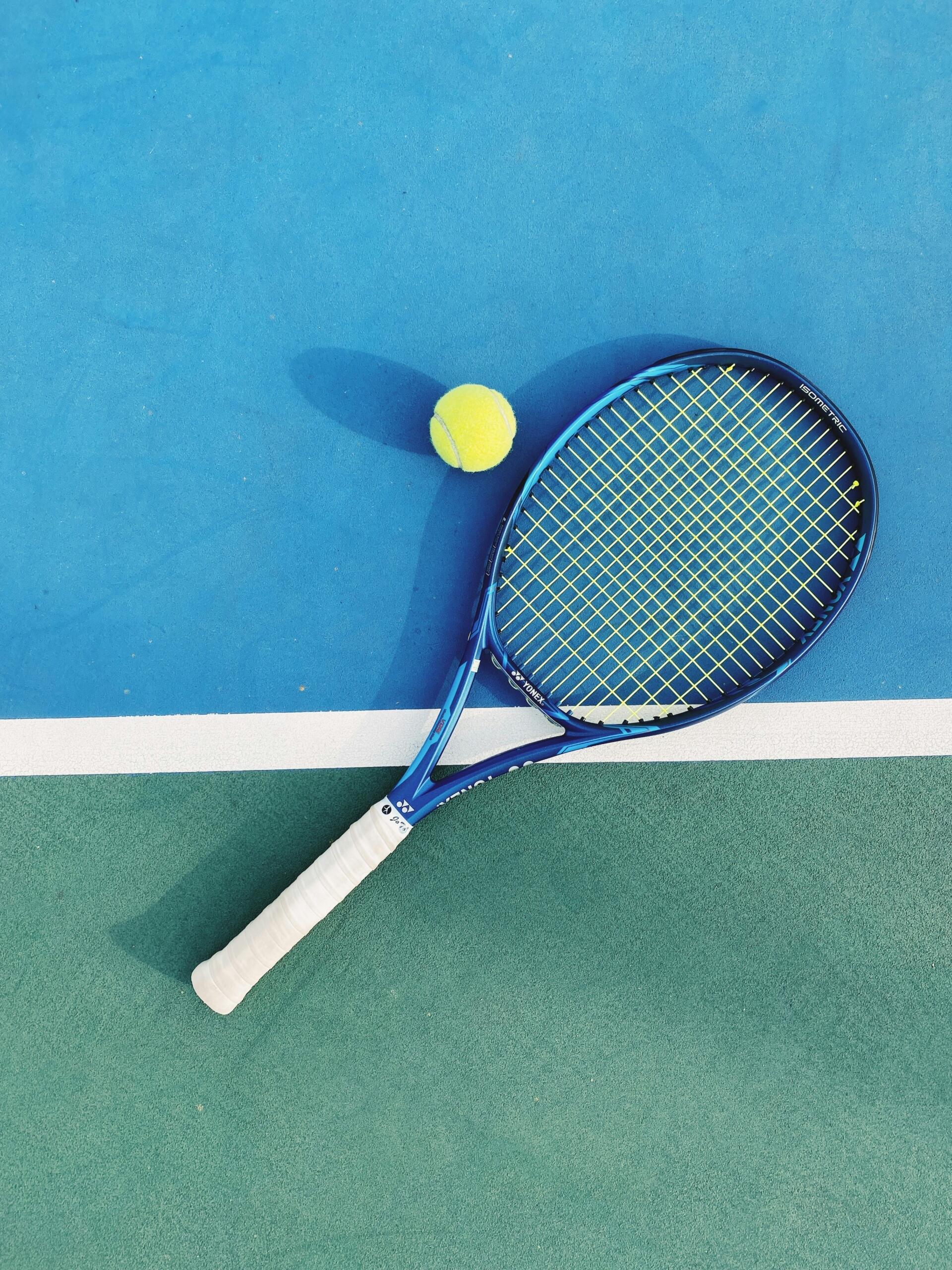 raqueta de tenis y pelota en una pista azul y verde