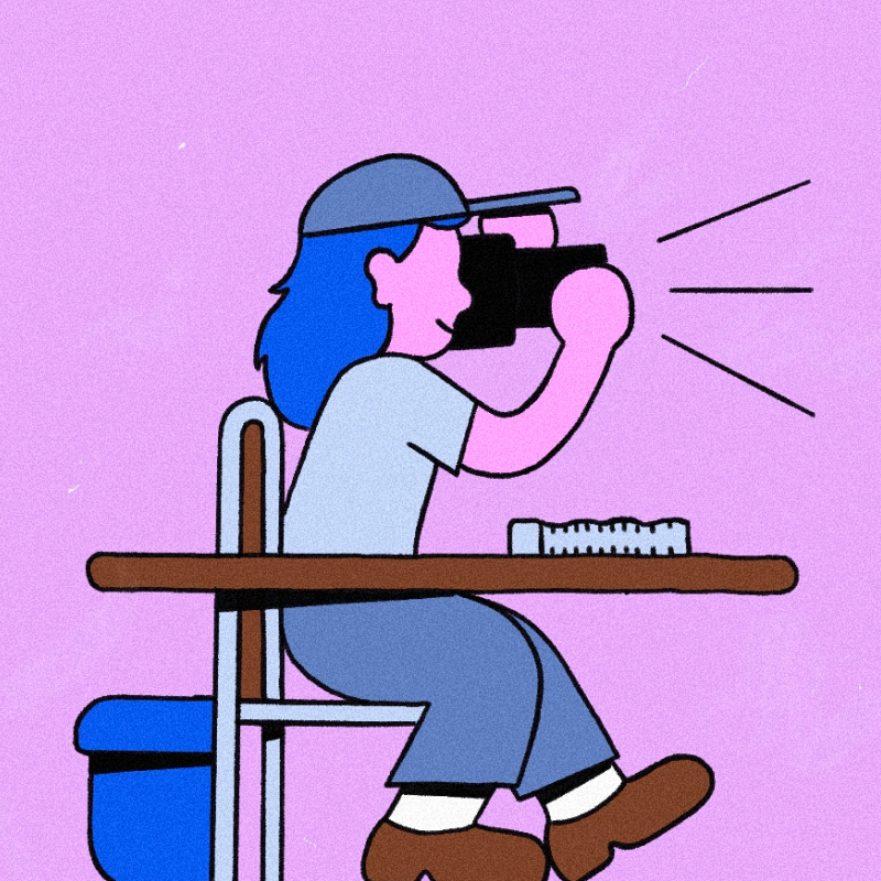 The photographer character sitting at a table and taking pictures