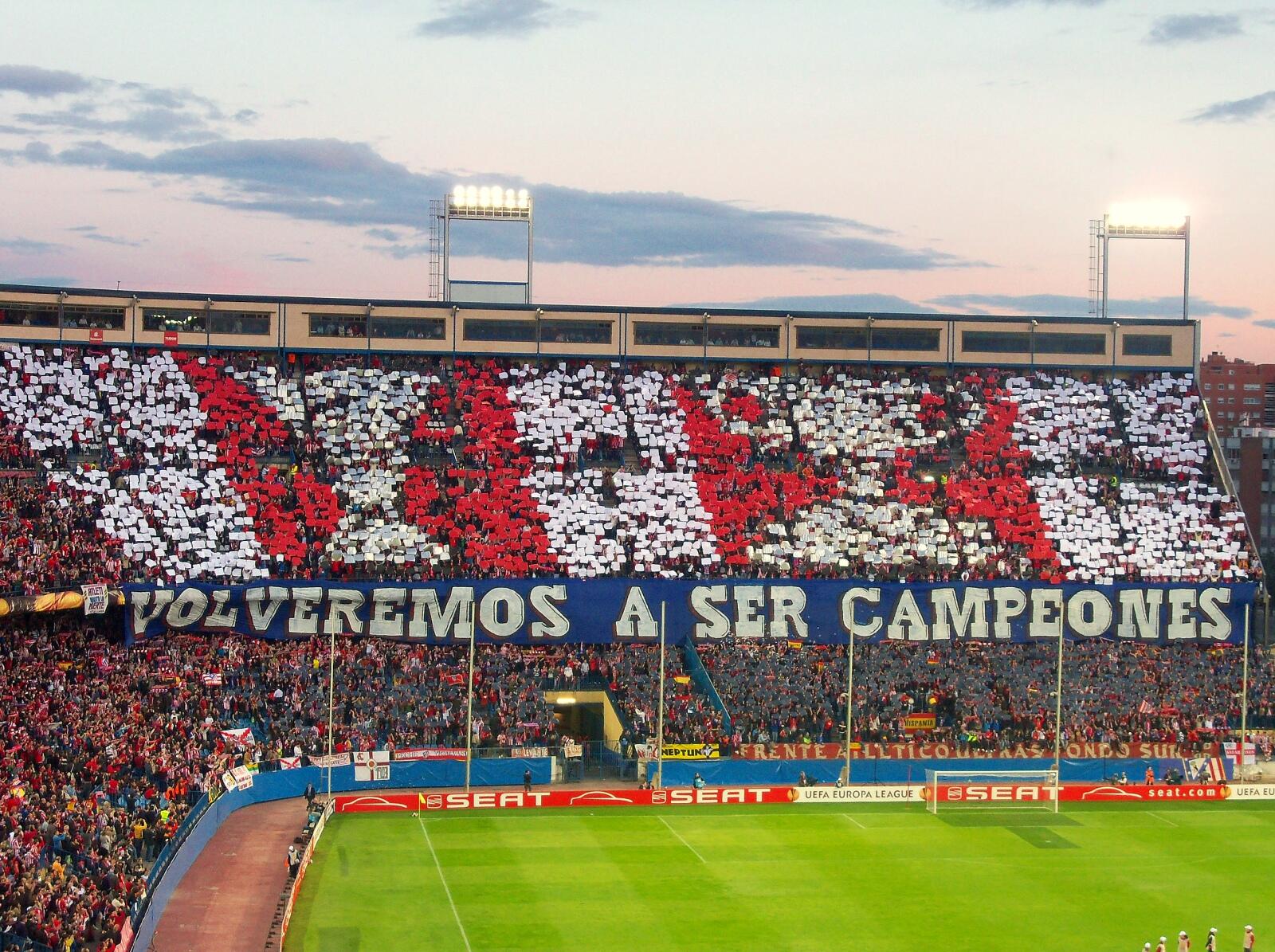Un vibrante despliegue en el estadio del atletico de madrid uestra a los aficionados con cartulinas rojas, blancas y azules en las que se lee «Volveremos a ser campeones», animando a su equipo.