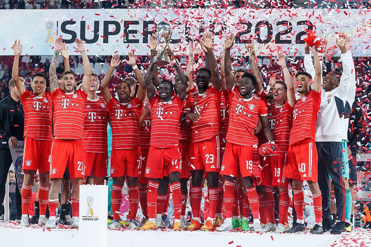 el bayern de municht celebrando una victoria con camisetas rojas sostiene un trofeo en medio de una lluvia de confeti, celebrando su victoria en la Supercopa.