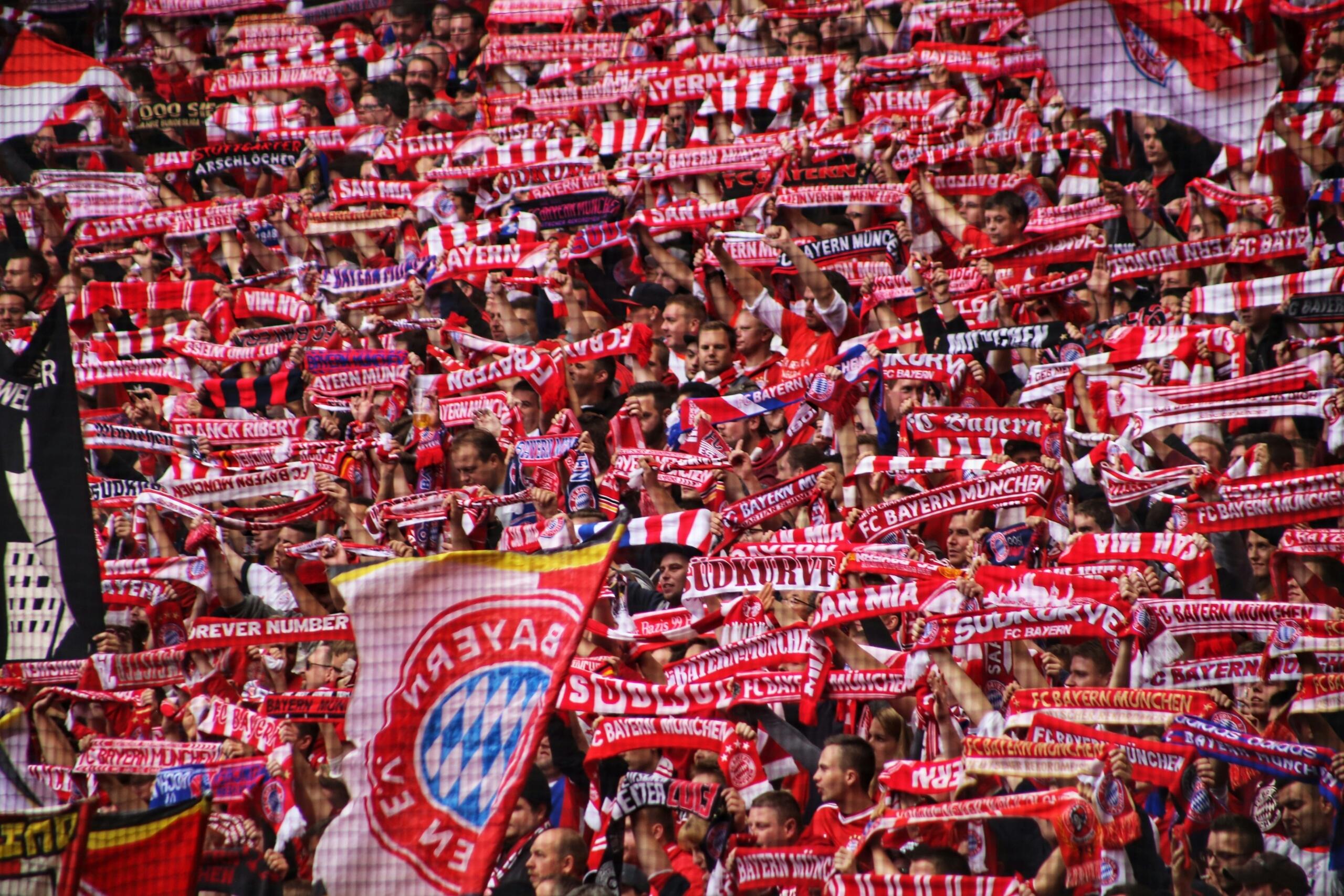 Una vibrante multitud de seguidores del FC Bayern de Múnich ondea numerosas bufandas y banderas rojas, creando un mar de espíritu de equipo y entusiasmo.