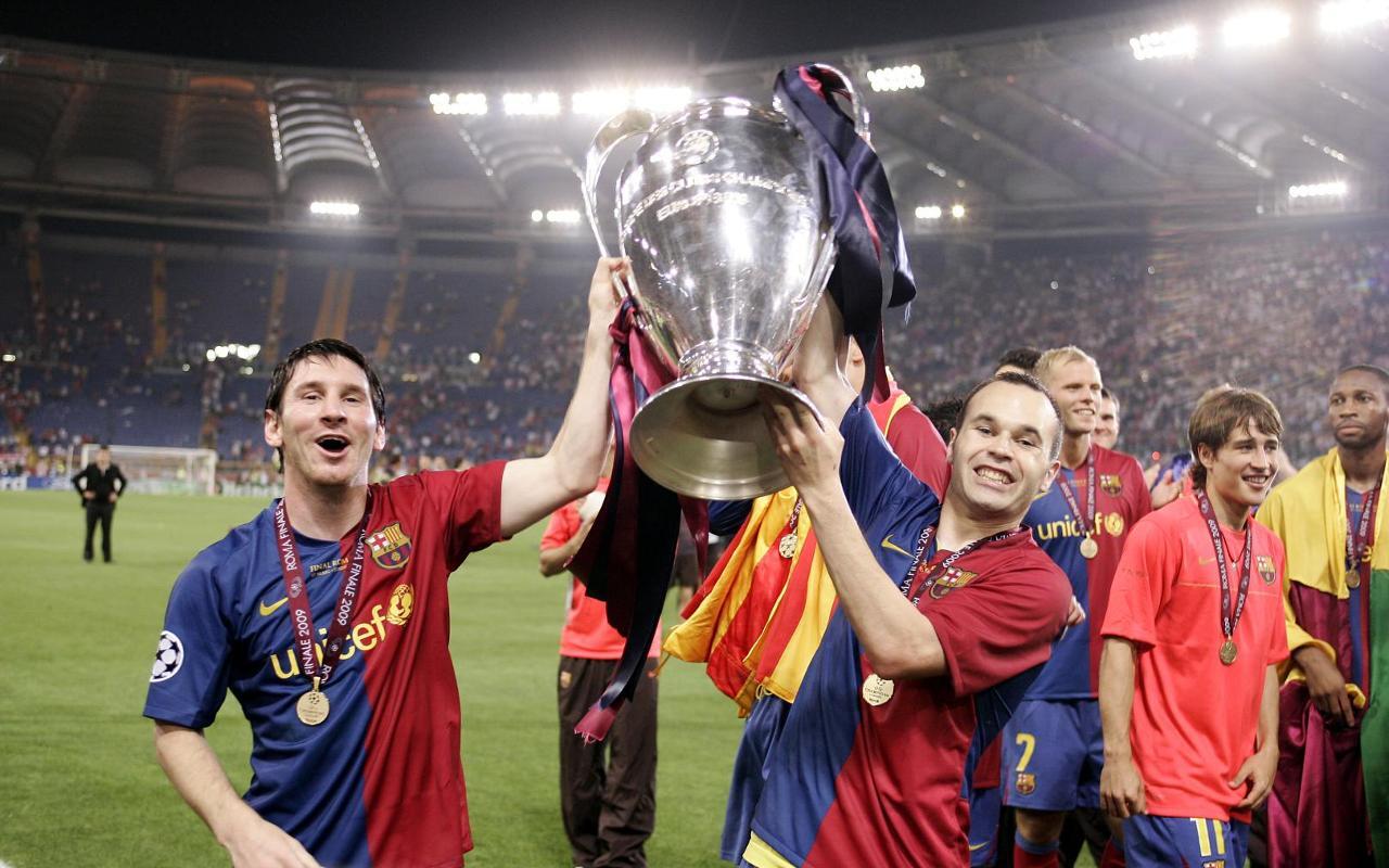 Los futbolistas mesi e iniesta levantan el trofeo de la Liga de Campeones, adornado con medallas, celebrando un momento victorioso en el campo.