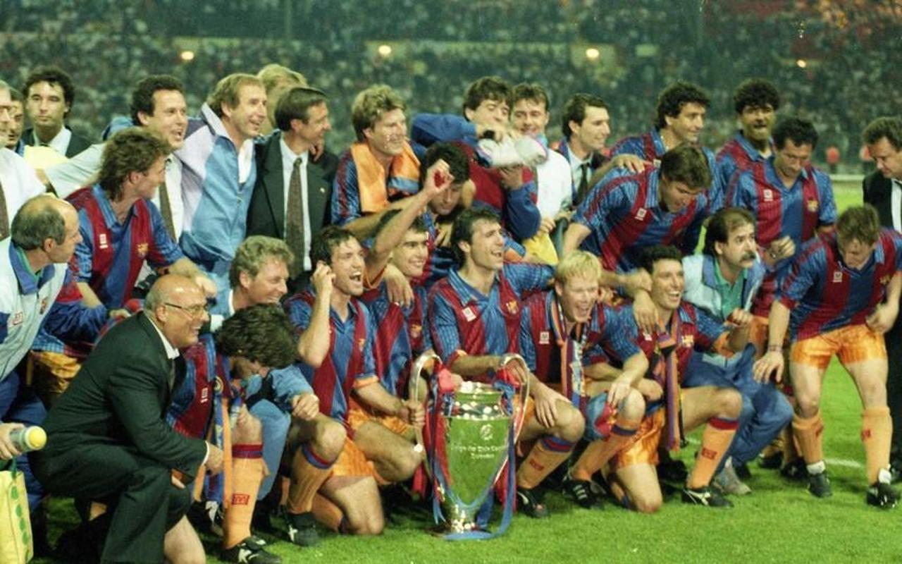 El equipo de fútbol del Barcelona celebra la victoria en el campeonato, sosteniendo el trofeo en medio del júbilo de sus compañeros, vestidos con camisetas azules y rojas.