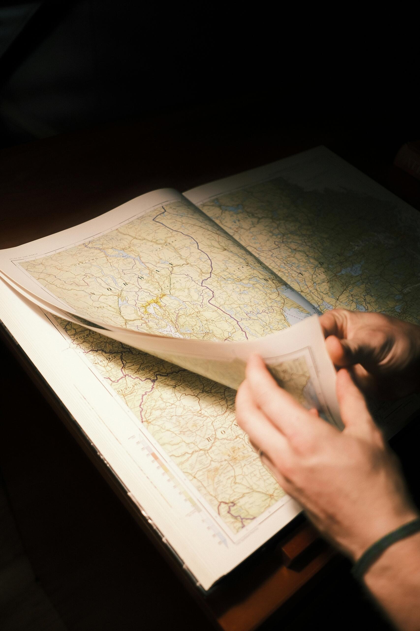 Persona hojeando un libro de mapas.