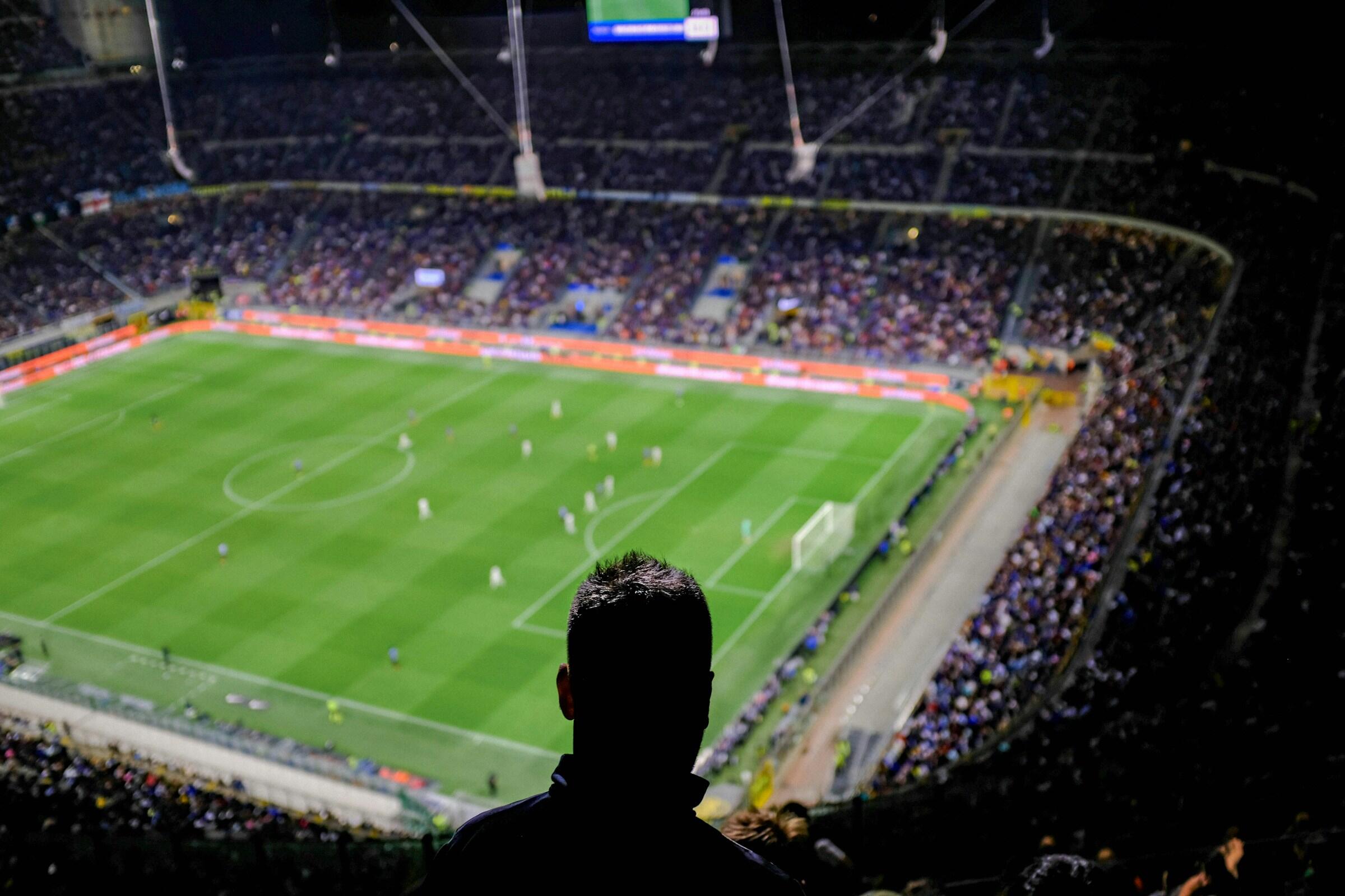 Un espectador observa un animado partido de fútbol desde las gradas del estadio del san siro del ac milan