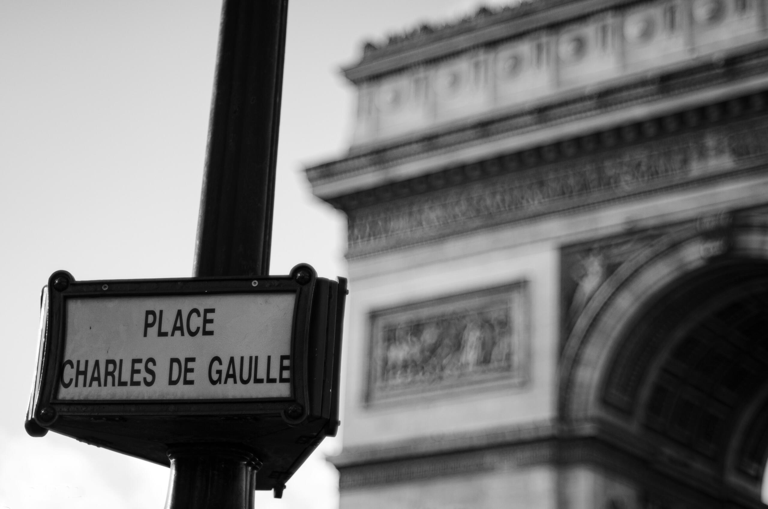 Señal de la plaza Charles de Gaulle con el Arco del Triunfo difuminado al fondo, captada en blanco y negro.