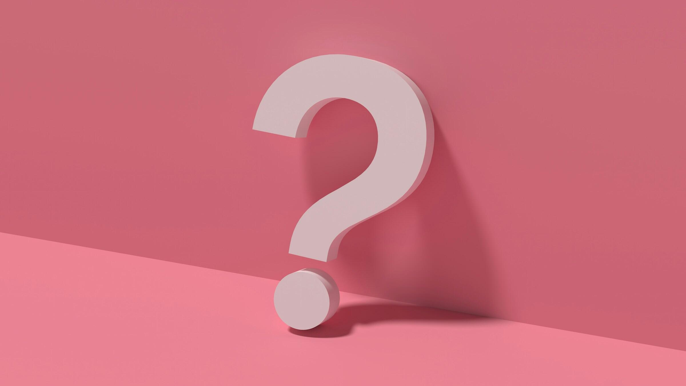 Un gran signo de interrogación rosa pálido se alza sobre un fondo rosa suave, proyectando una sombra sutil sobre la superficie debajo